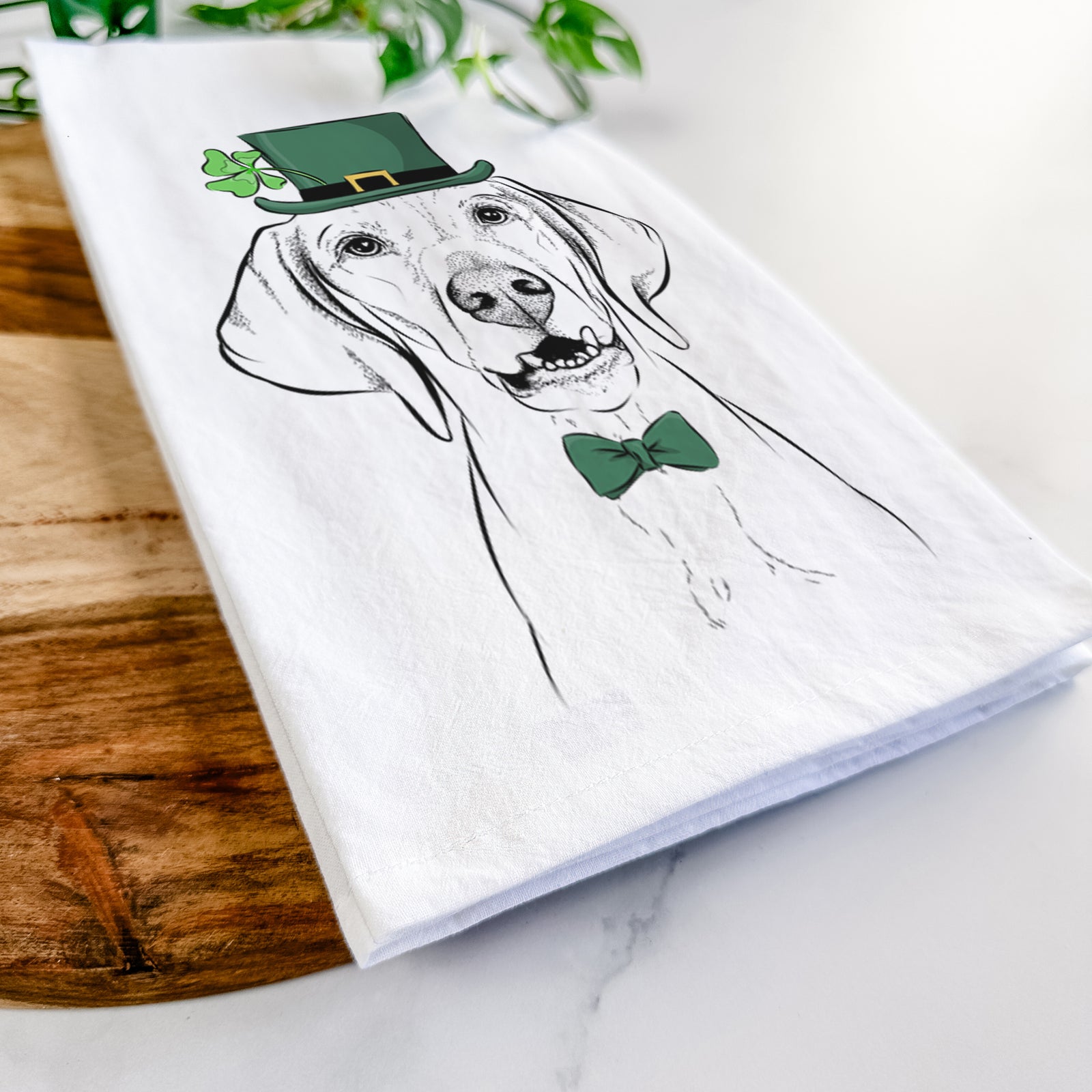 Hand-drawn sketch of Sarge the Vizsla wearing a St. Patrick's Day leprechaun hat and bow tie on a tea towel