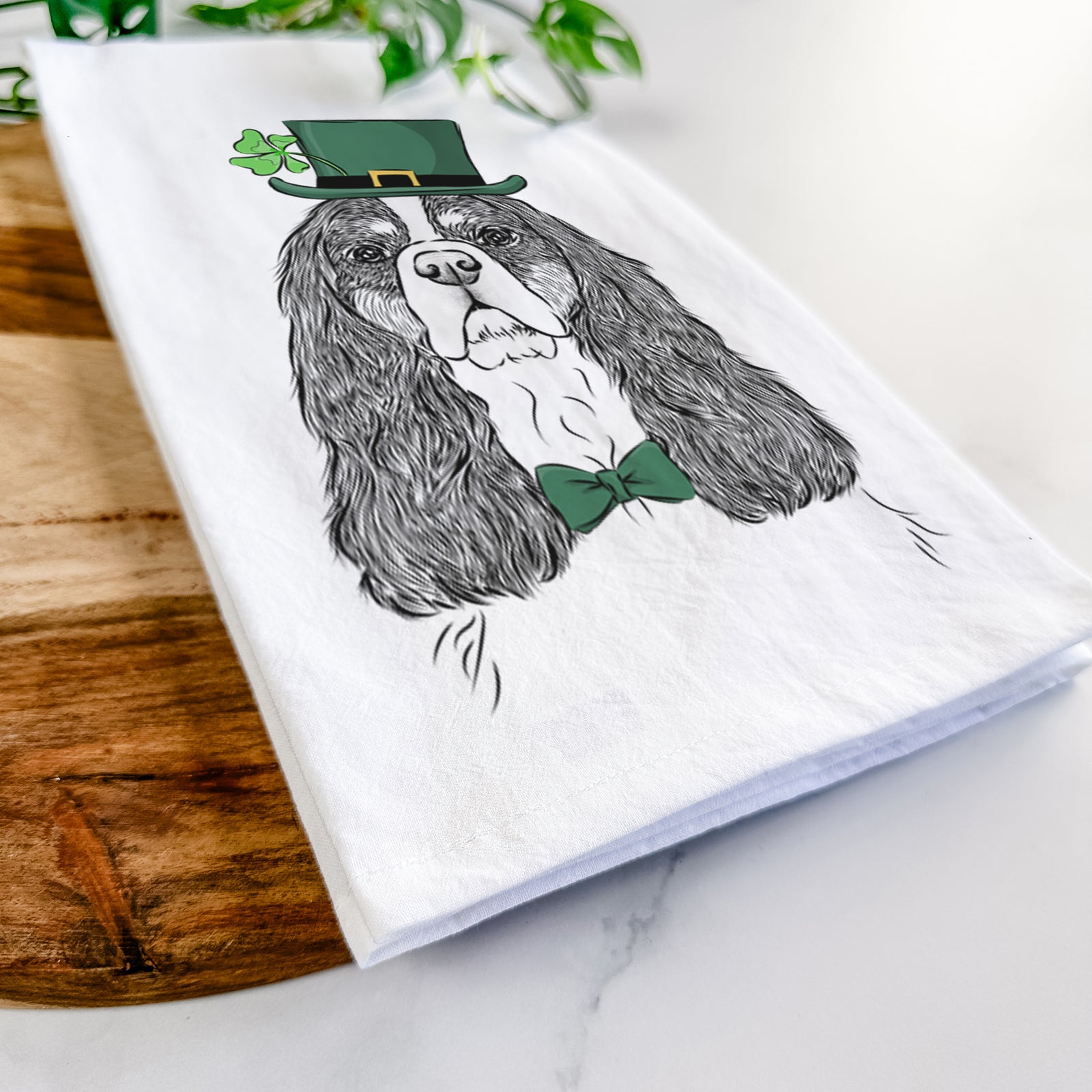 Hand-drawn sketch of Sebastian the Cavalier King Charles Spaniel wearing a St. Patrick's Day leprechaun hat and bow tie on a tea towel