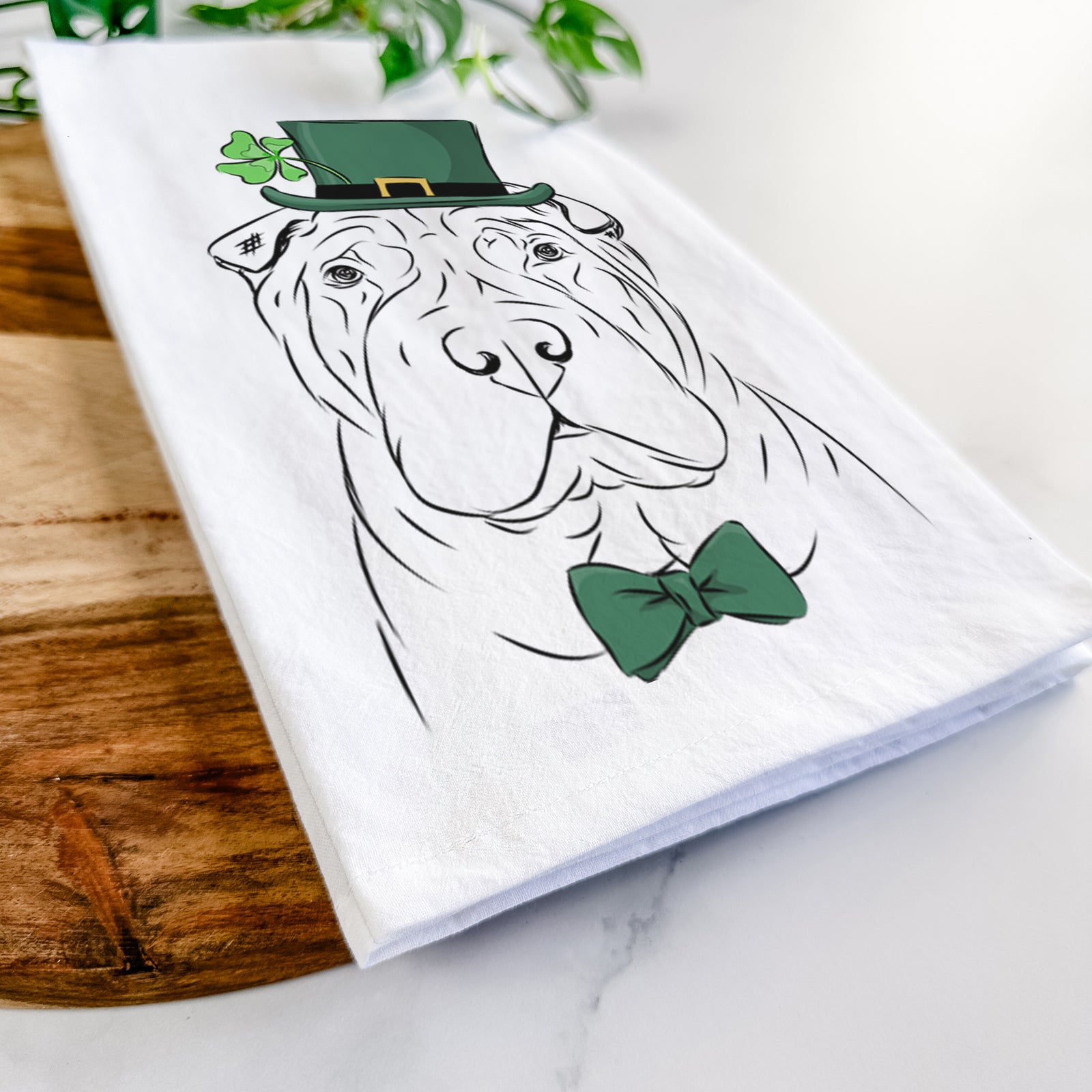 Hand-drawn sketch of Sharpy the Shar Pei wearing a St. Patrick's Day leprechaun hat and bow tie on a tea towel
