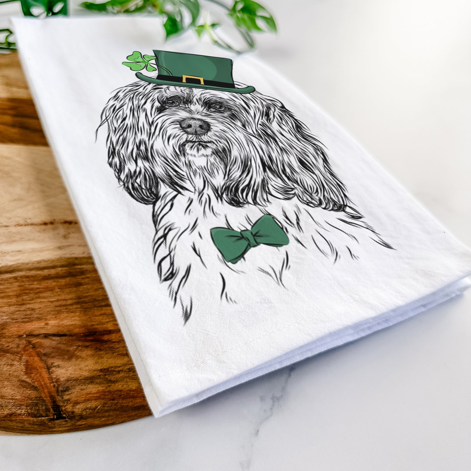 Hand-drawn sketch of Shenpa the Tibetan Terrier wearing a St. Patrick's Day leprechaun hat and bow tie on a tea towel