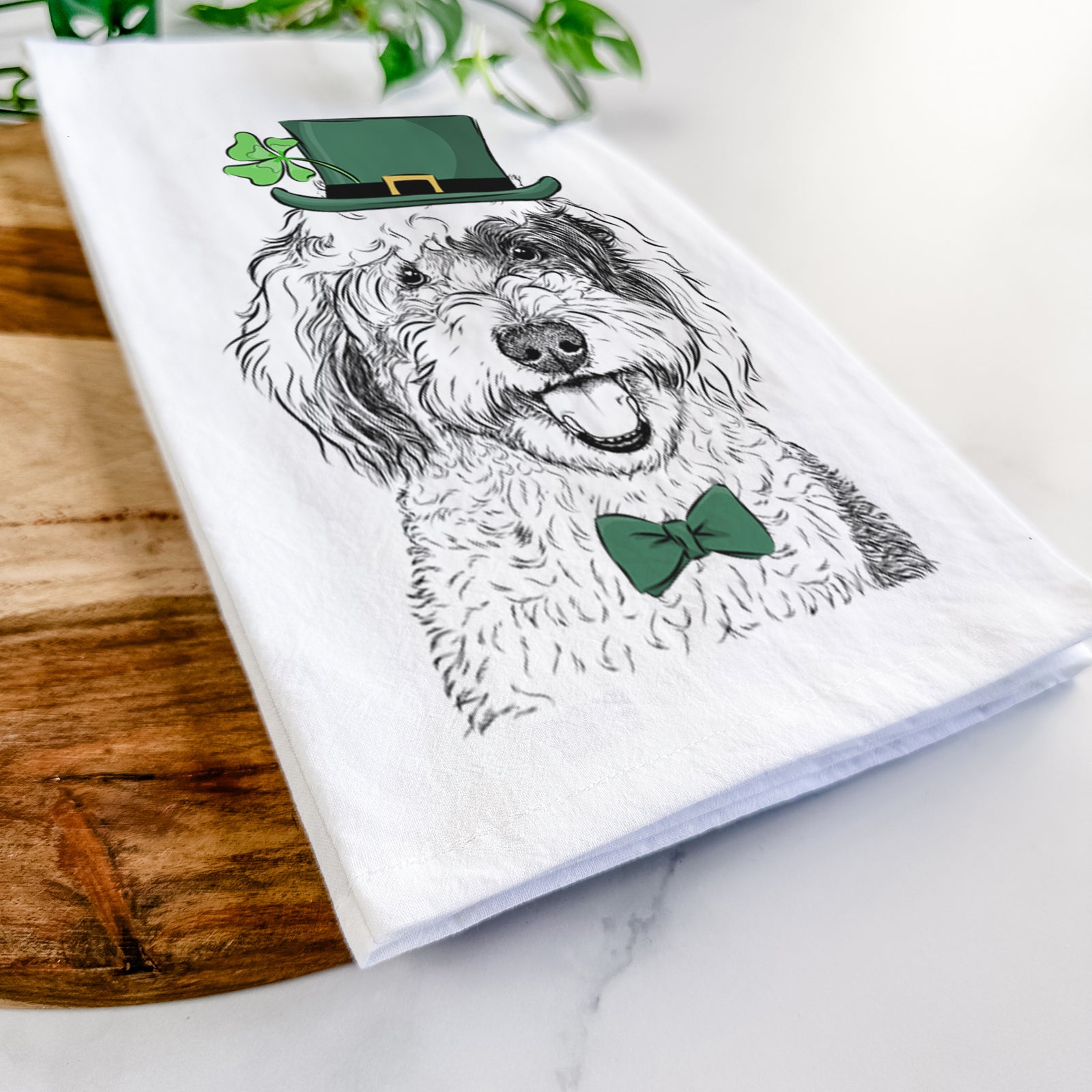 Hand-drawn sketch of Sherlock the Sheepadoodle wearing a St. Patrick's Day leprechaun hat and bow tie on a tea towel