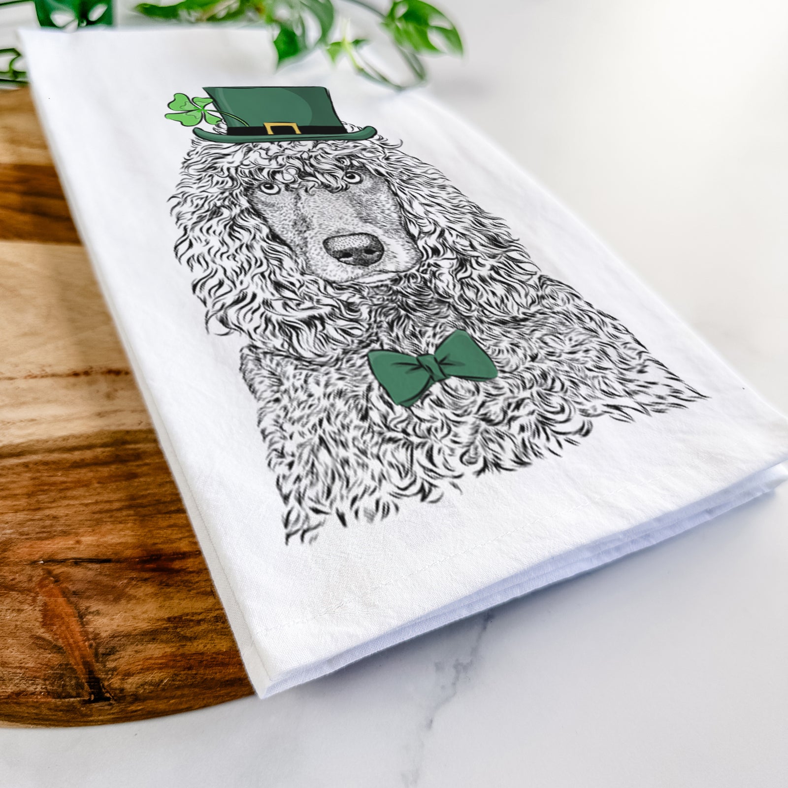 Hand-drawn sketch of Shilo the Irish Water Spaniel wearing a St. Patrick's Day leprechaun hat and bow tie on a tea towel