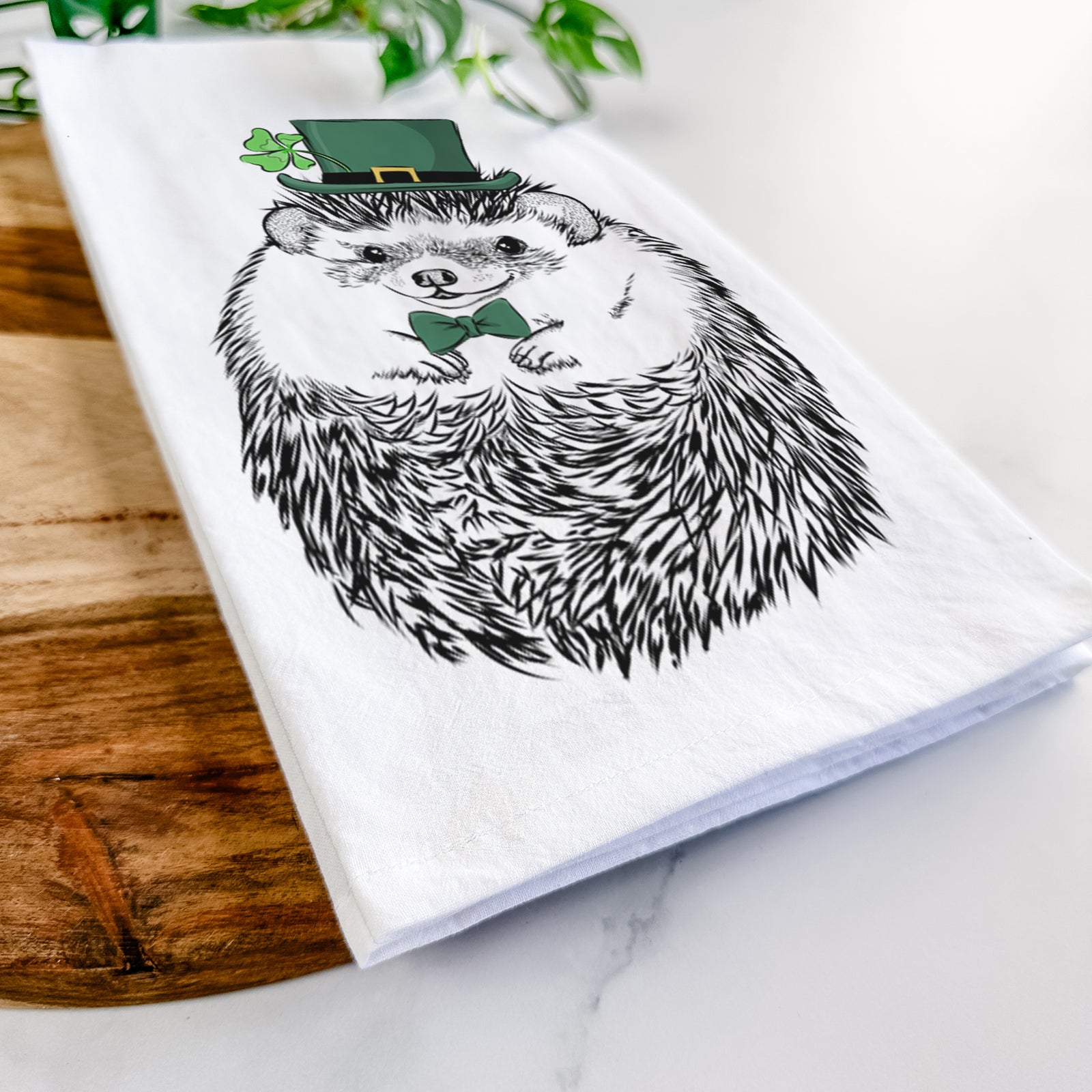 Hand-drawn sketch of Sid the Hedgehog wearing a St. Patrick's Day leprechaun hat and bow tie on a tea towel