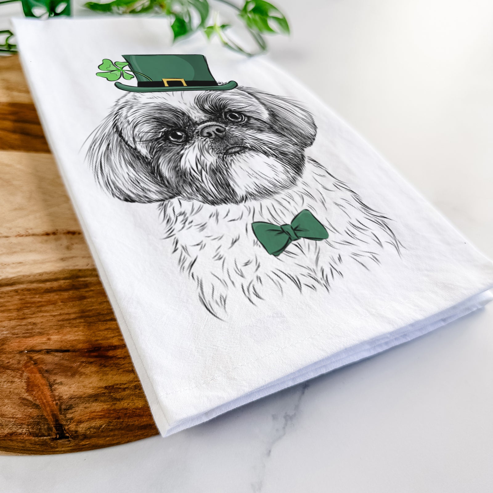 Hand-drawn sketch of Simon the Shih Tzu wearing a St. Patrick's Day leprechaun hat and bow tie on a tea towel