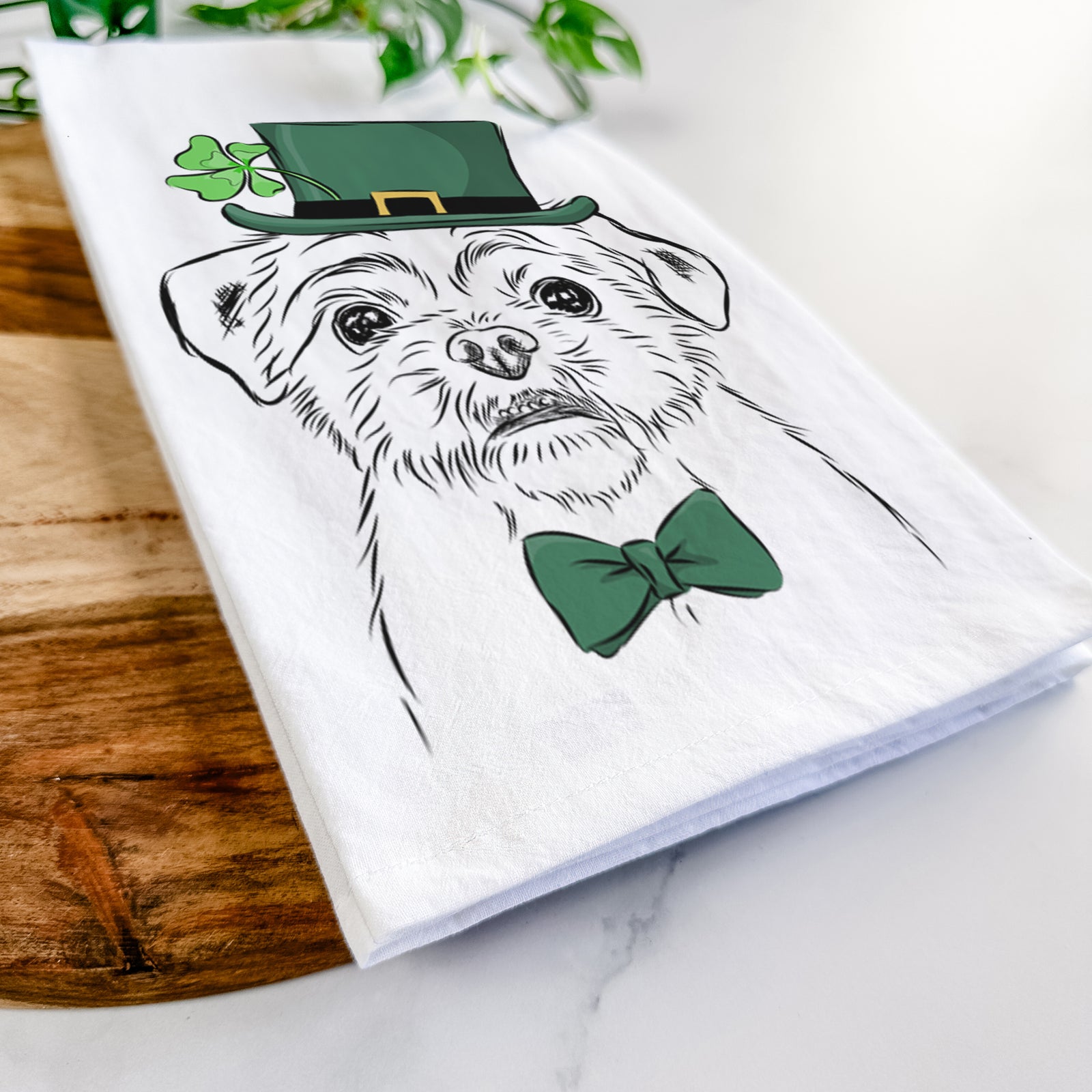 Hand-drawn sketch of Smash the Shih Tzu wearing a St. Patrick's Day leprechaun hat and bow tie on a tea towel