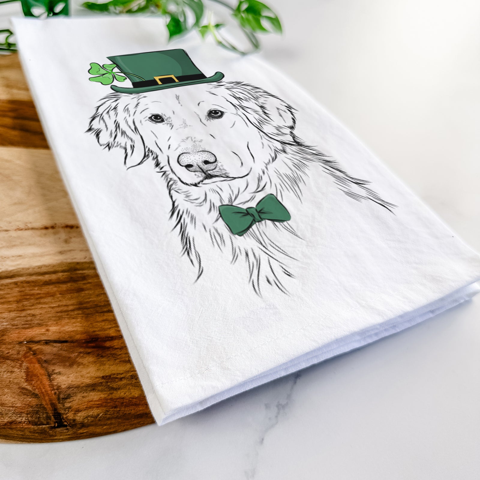 Hand-drawn sketch of Spencer the Golden Retriever wearing a St. Patrick's Day leprechaun hat and bow tie on a tea towel