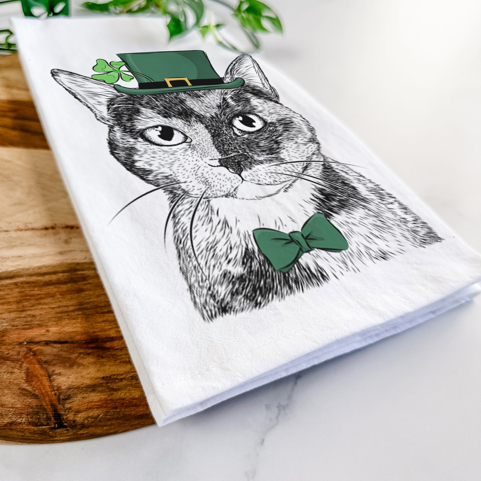 Hand-drawn sketch of Spooky Kitty the Tortoiseshell Cat wearing a St. Patrick's Day leprechaun hat and bow tie on a tea towel