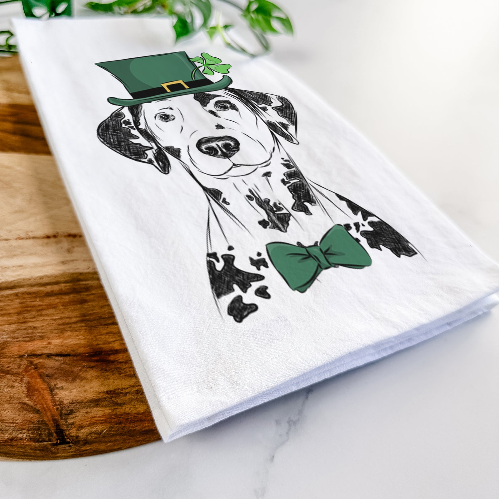 Hand-drawn sketch of Spot the Dalmatian wearing a St. Patrick's Day leprechaun hat and bow tie on a tea towel