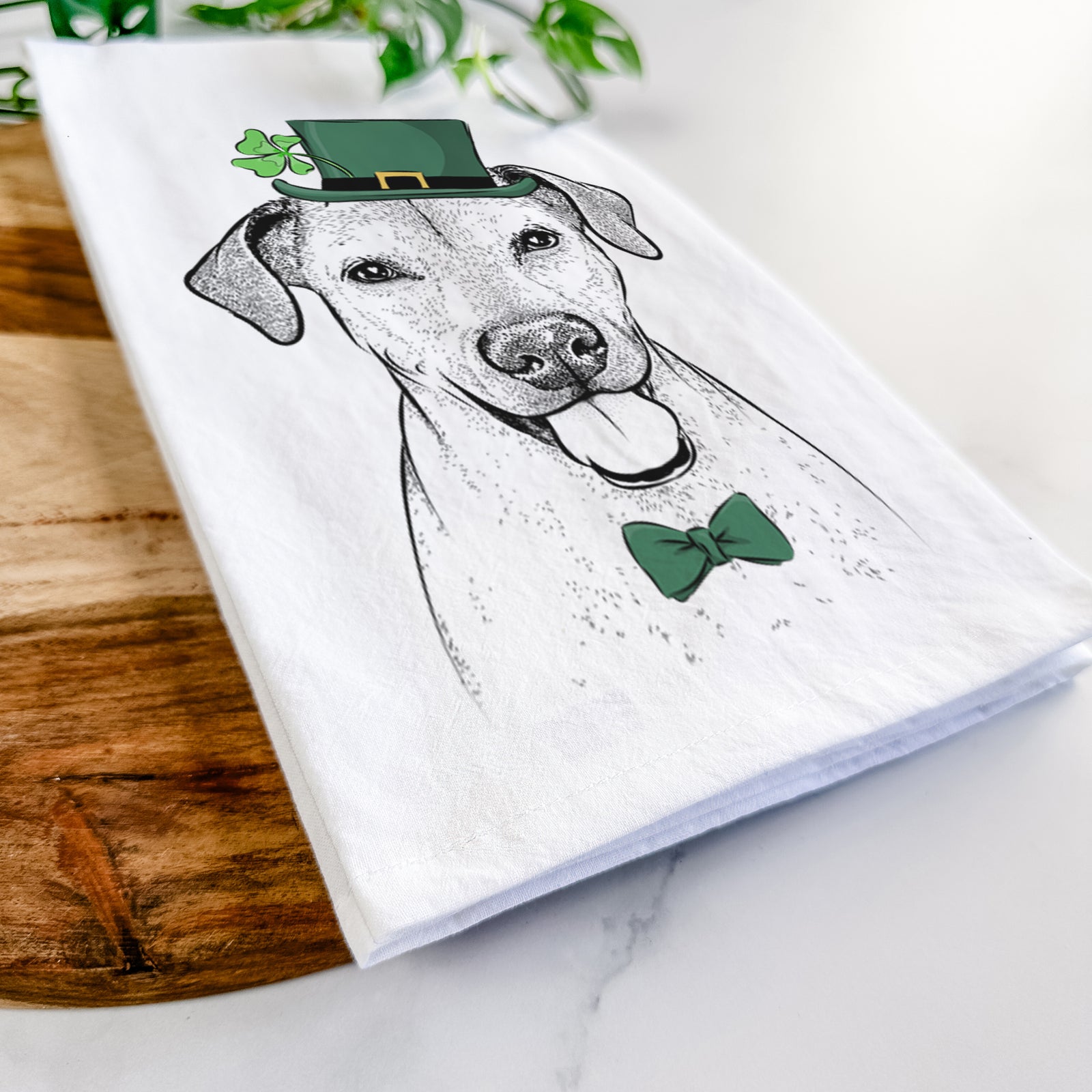 Hand-drawn sketch of Sugar the American Staffordshire Mix wearing a St. Patrick's Day leprechaun hat and bow tie on a tea towel