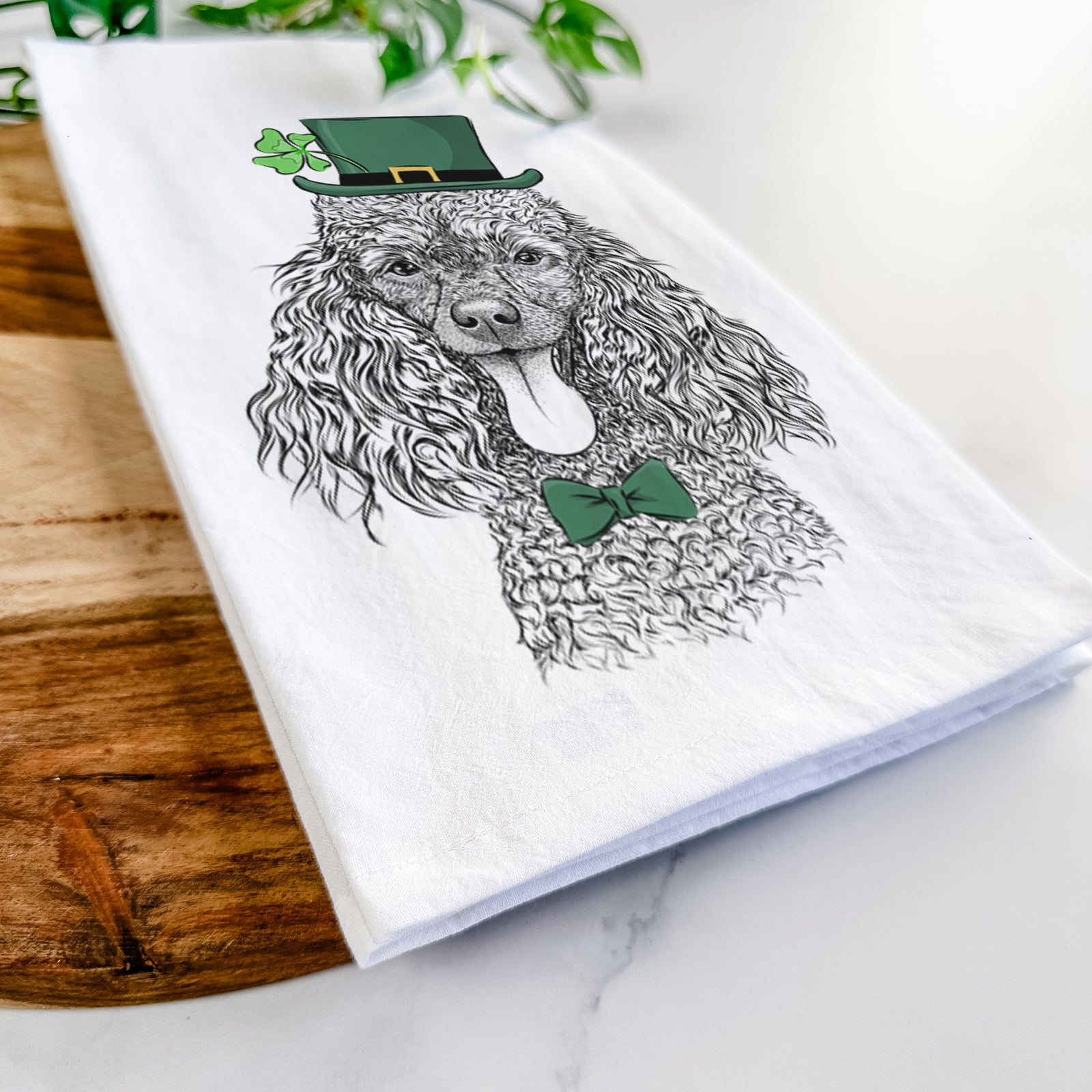 Hand-drawn sketch of Teddy the Mini Poodle wearing a St. Patrick's Day leprechaun hat and bow tie on a tea towel