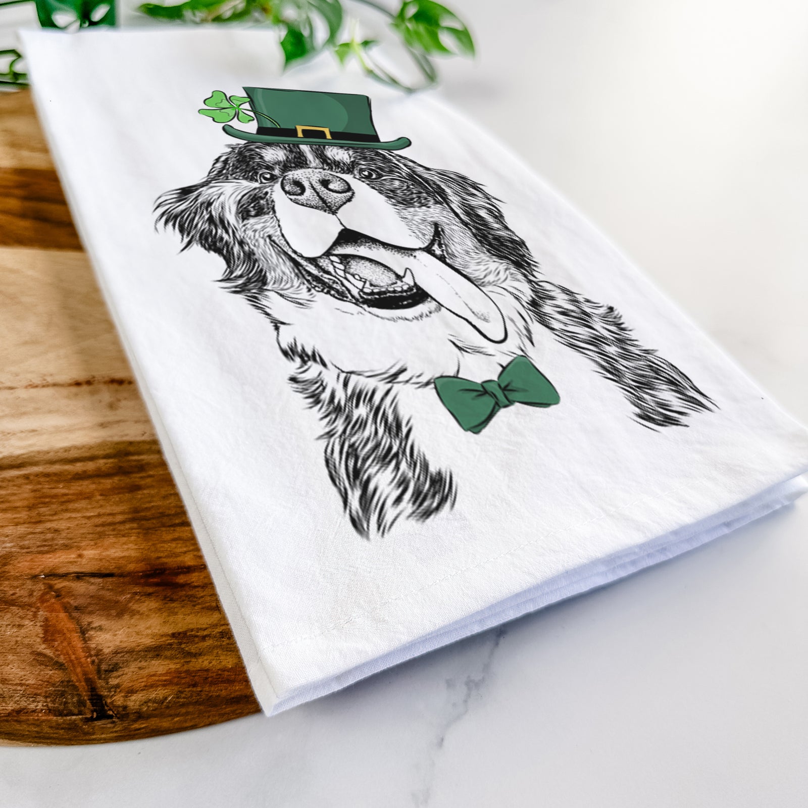 Hand-drawn sketch of Theo the Bernese Mountain Dog wearing a St. Patrick's Day leprechaun hat and bow tie on a tea towel