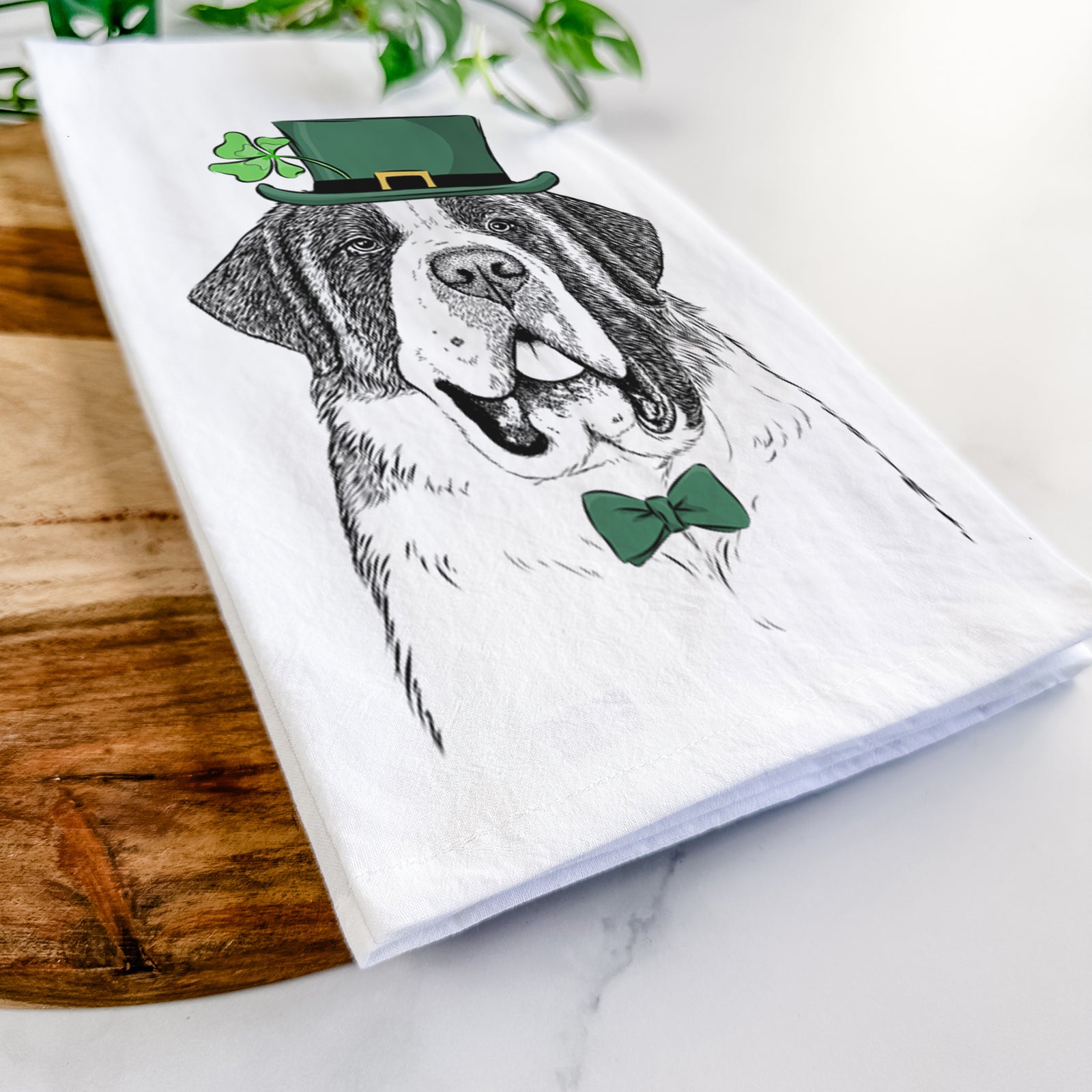Hand-drawn sketch of Thor the Saint Bernard wearing a St. Patrick's Day leprechaun hat and bow tie on a tea towel