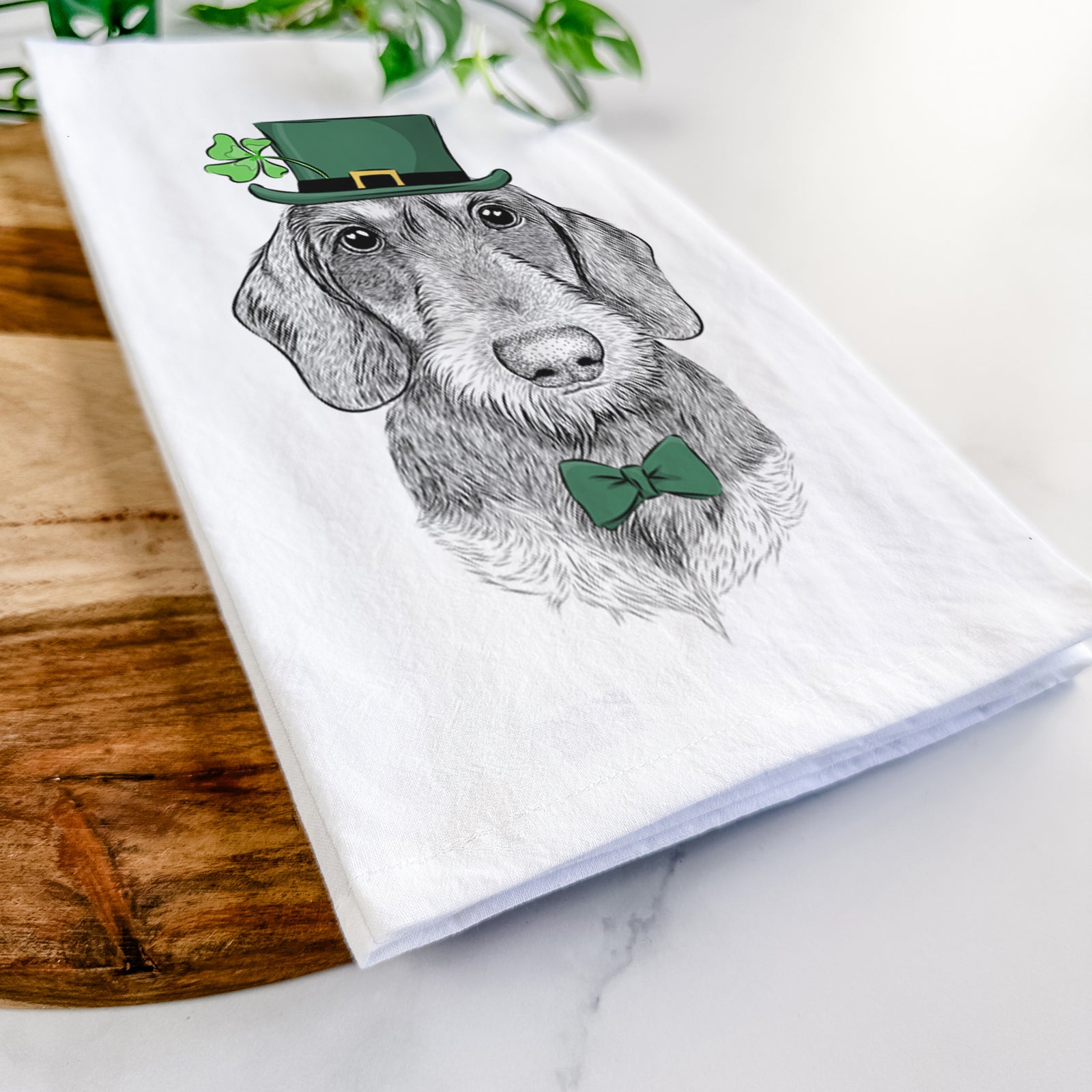 Hand-drawn sketch of Truman the Wirehaired Dachshund wearing a St. Patrick's Day leprechaun hat and bow tie on a tea towel
