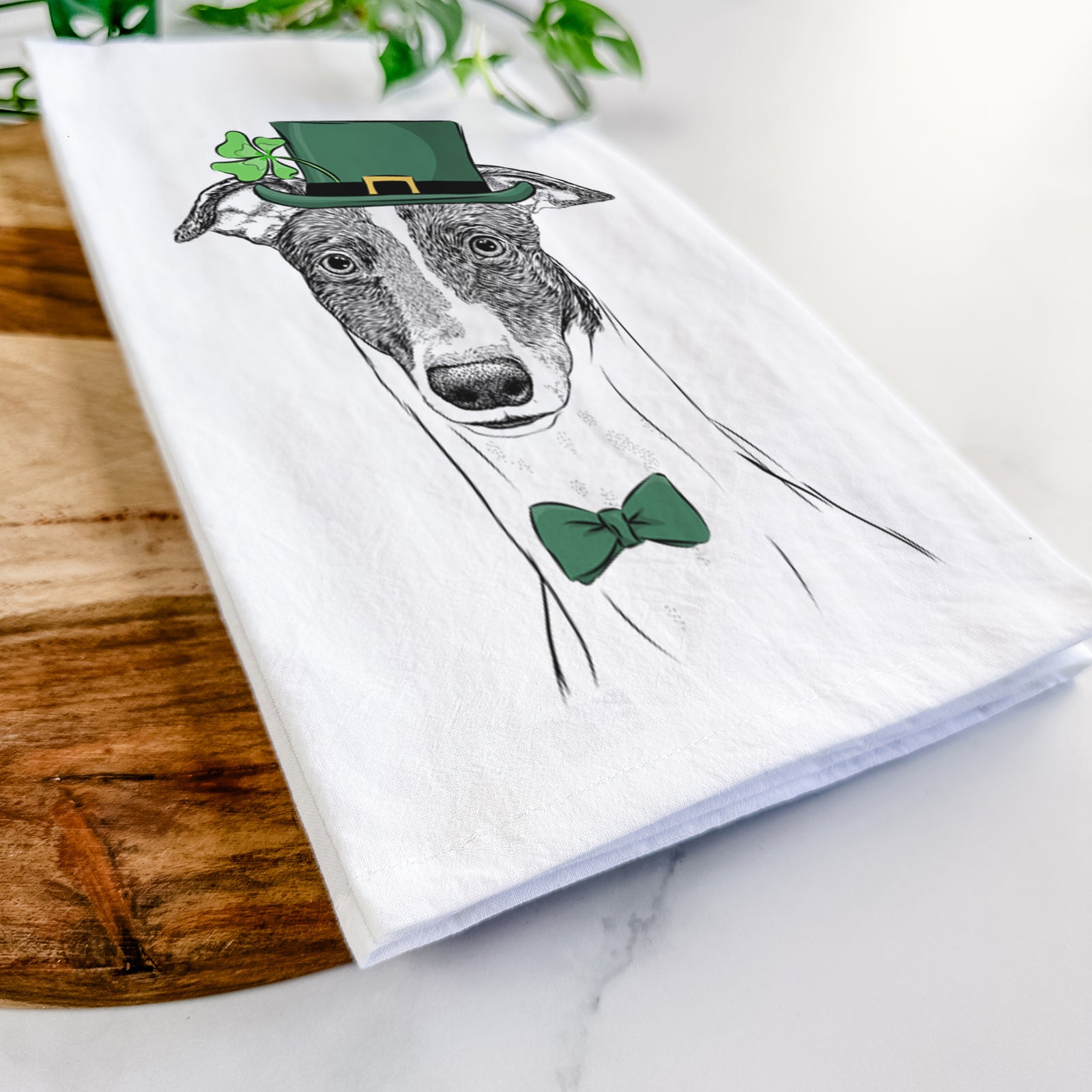 Hand-drawn sketch of Vyncent the Greyhound wearing a St. Patrick's Day leprechaun hat and bow tie on a tea towel