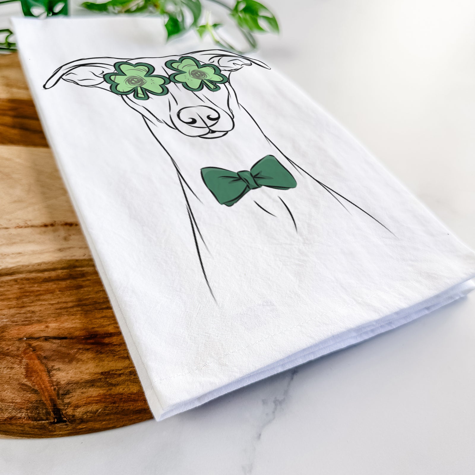 Hand-drawn sketch of Wallace the Whippet wearing a St. Patrick's Day leprechaun hat and bow tie on a tea towel