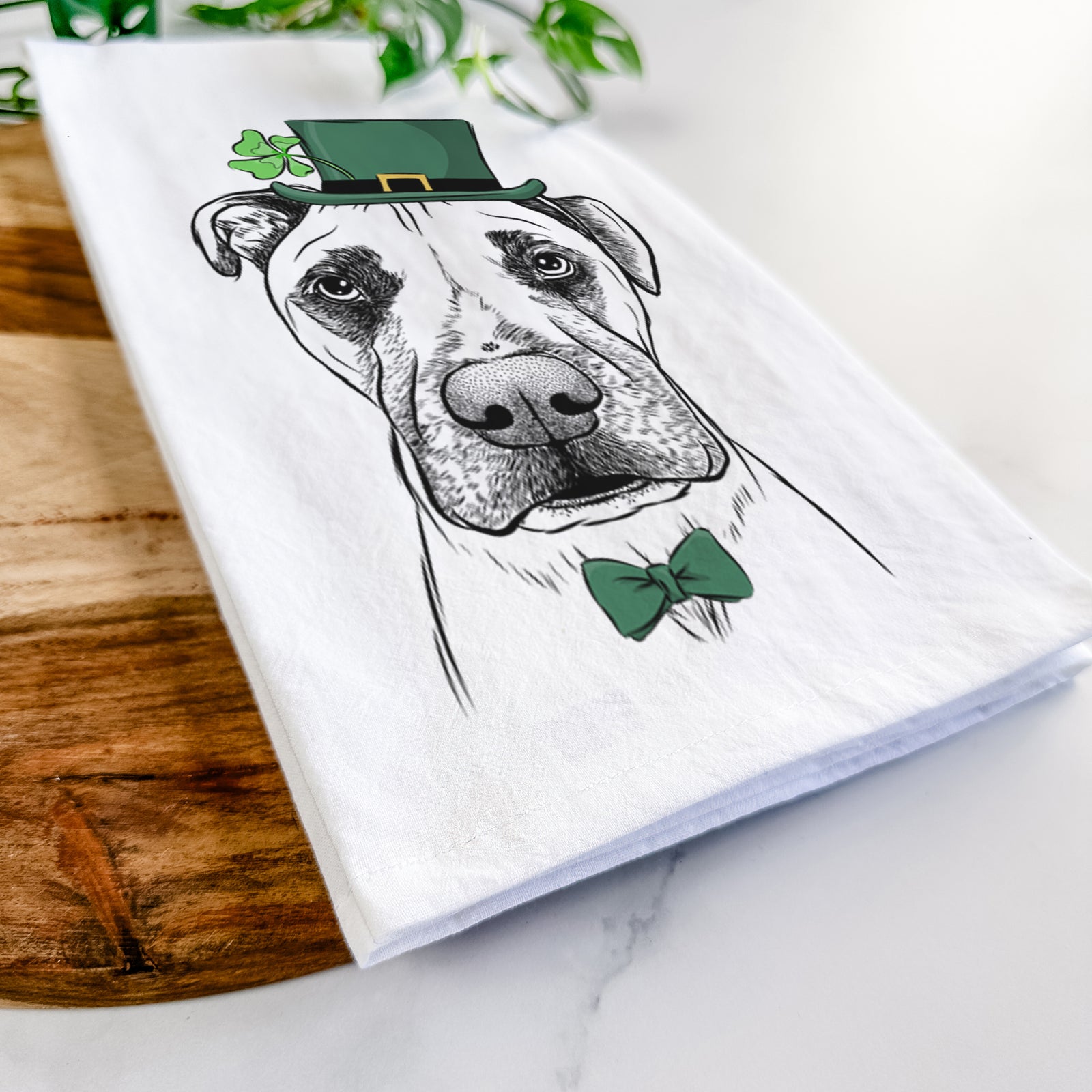 Hand-drawn sketch of Waylon the Boxane wearing a St. Patrick's Day leprechaun hat and bow tie on a tea towel