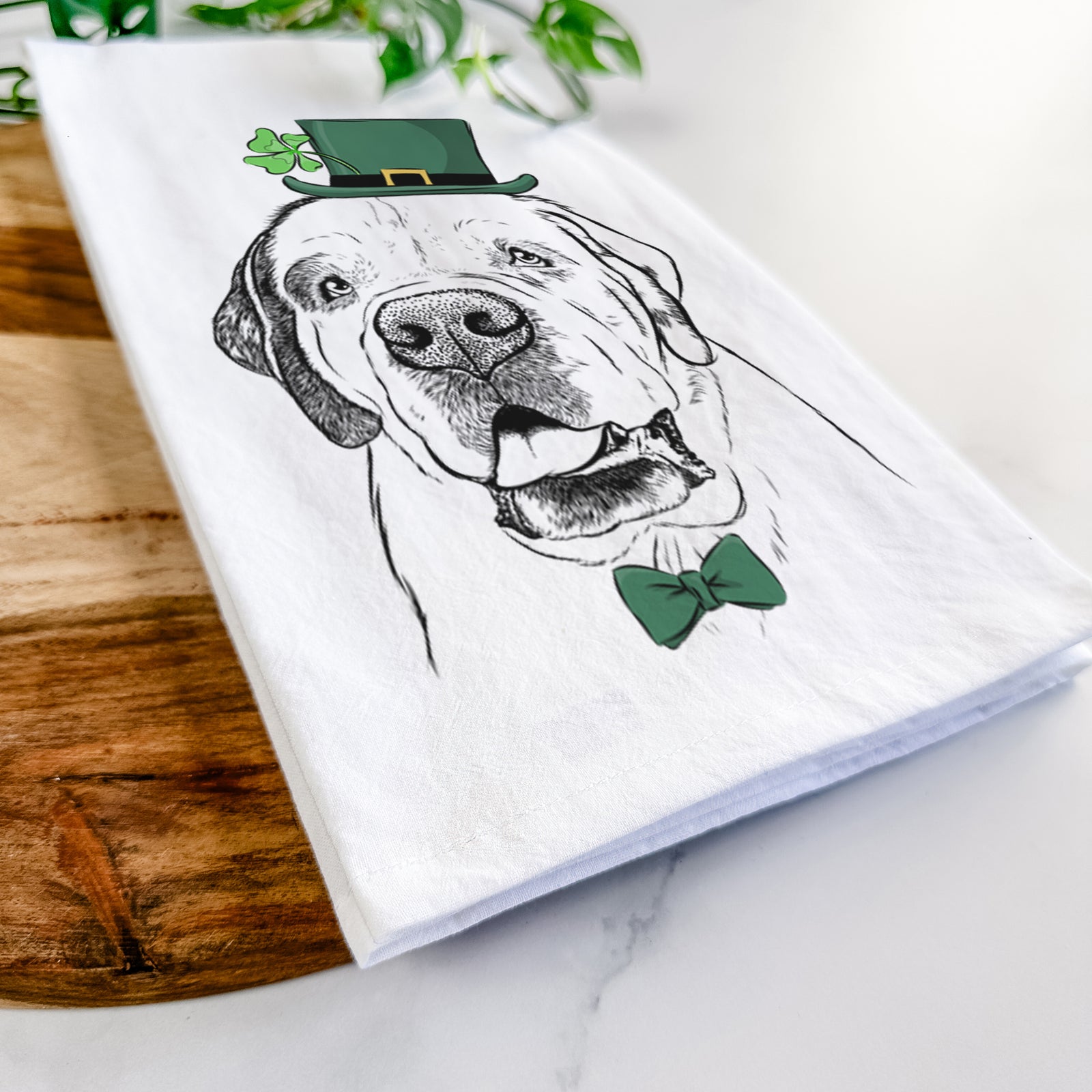 Hand-drawn sketch of Wendy the Saint Bernard wearing a St. Patrick's Day leprechaun hat and bow tie on a tea towel