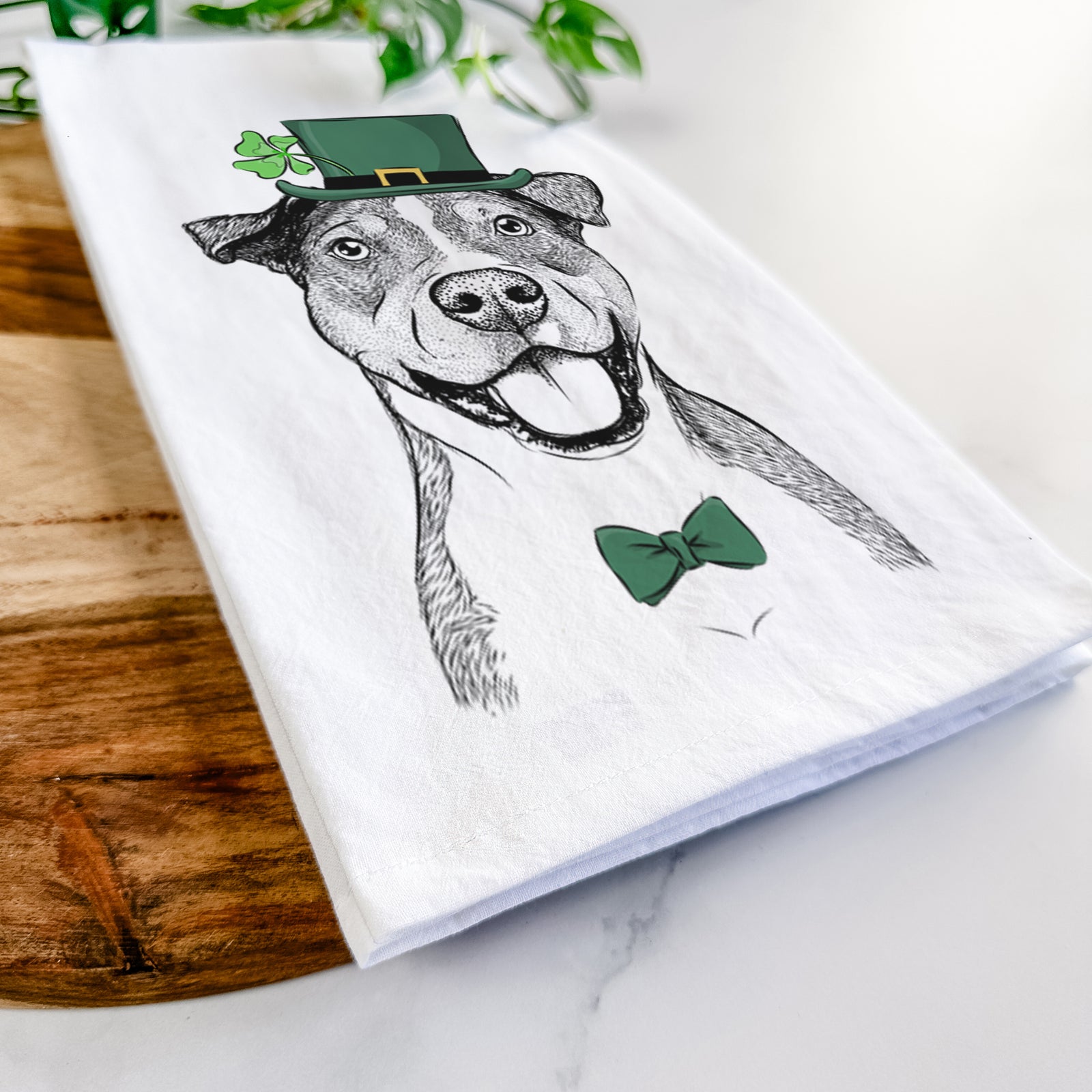 Hand-drawn sketch of Wendy the Mixed Breed wearing a St. Patrick's Day leprechaun hat and bow tie on a tea towel