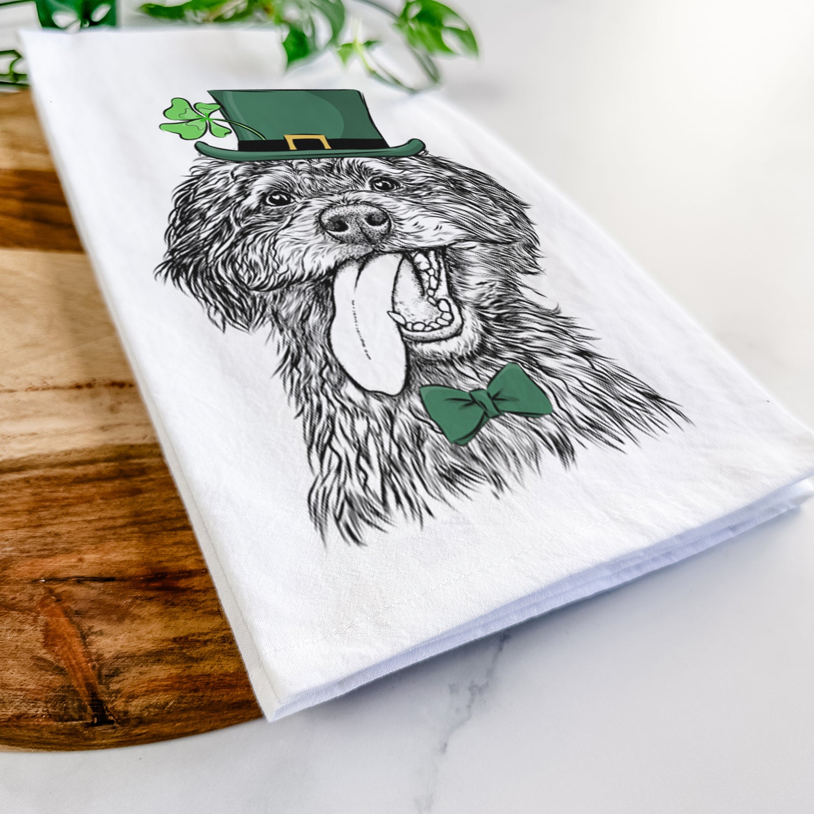 Hand-drawn sketch of Winnie the Mini Aussiedoodle wearing a St. Patrick's Day leprechaun hat and bow tie on a tea towel