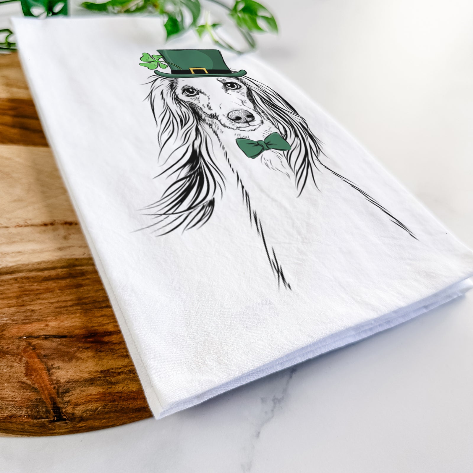 Hand-drawn sketch of Zahra the Saluki wearing a St. Patrick's Day leprechaun hat and bow tie on a tea towel