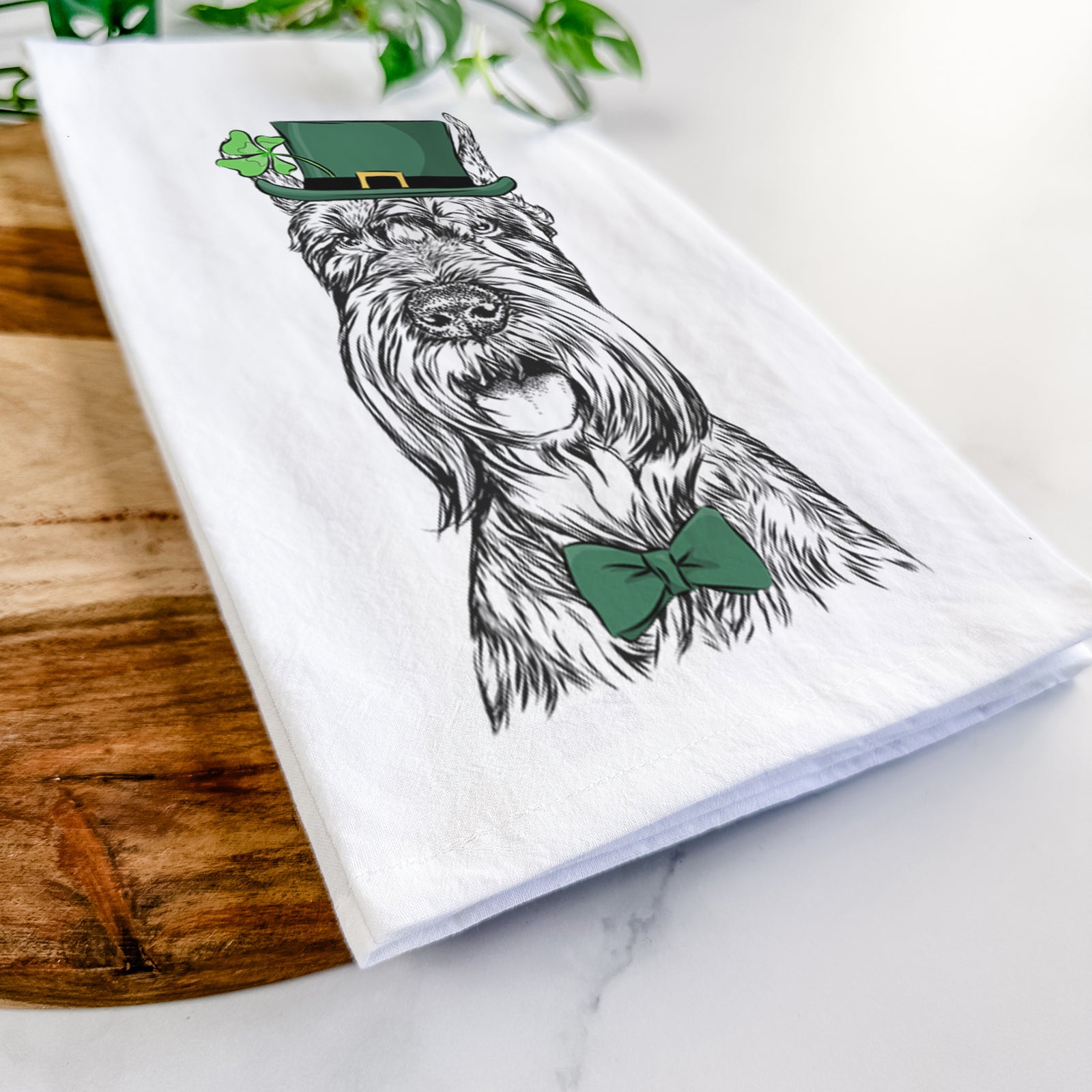 Hand-drawn sketch of Zuri the Giant Schnauzer wearing a St. Patrick's Day leprechaun hat and bow tie on a tea towel