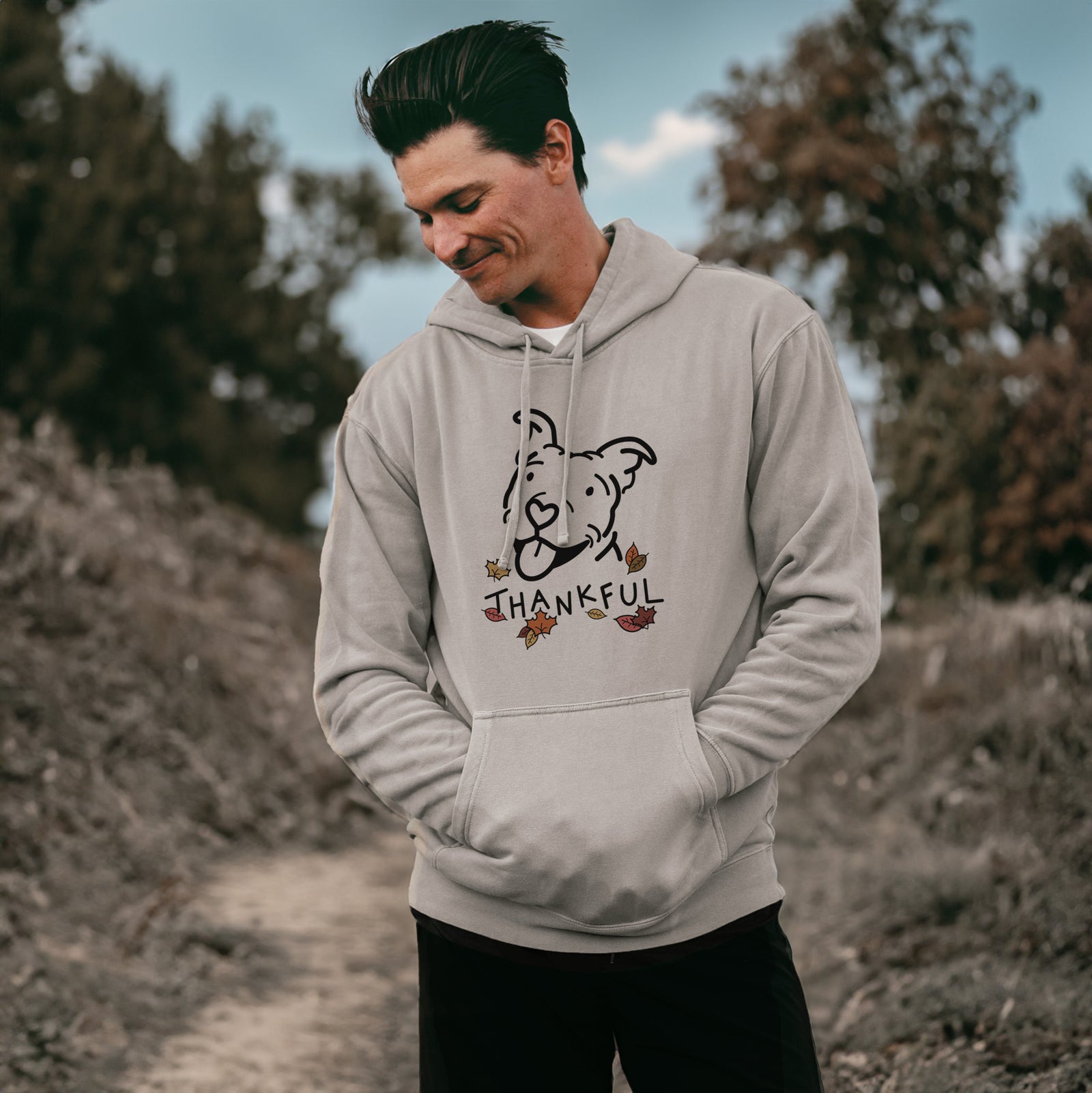 Minimalist line drawing of Arlo the Pitbull with 'Thankful' lettering on a Cement Unisex pigment dyed hoodie, worn by a man