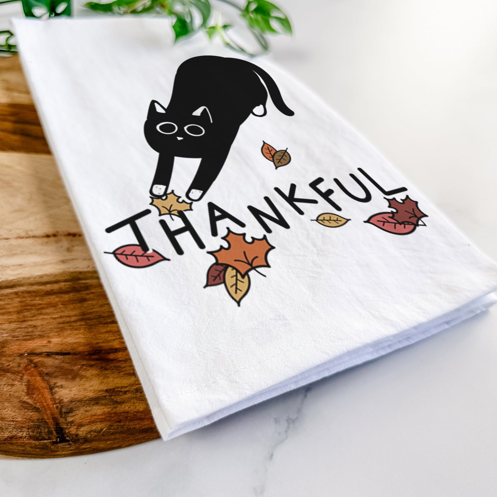 Minimalist line drawing of Bug the Black Cat with 'Thankful' lettering on a tea towel