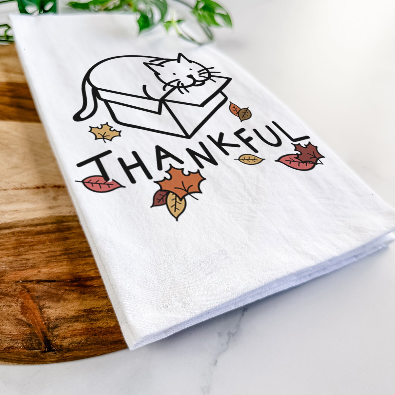 Minimalist line drawing of Charlie the Cat in a Box with 'Thankful' lettering on a tea towel