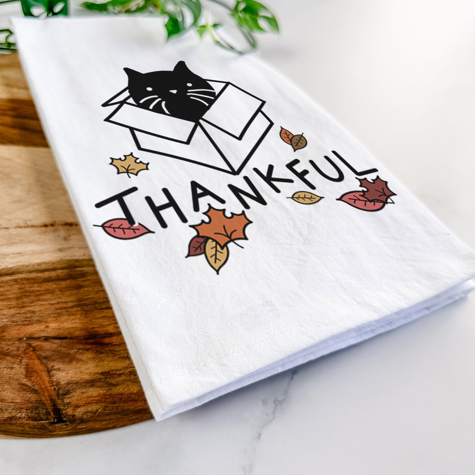 Minimalist line drawing of Doc the Black Cat in a Box with 'Thankful' lettering on a tea towel