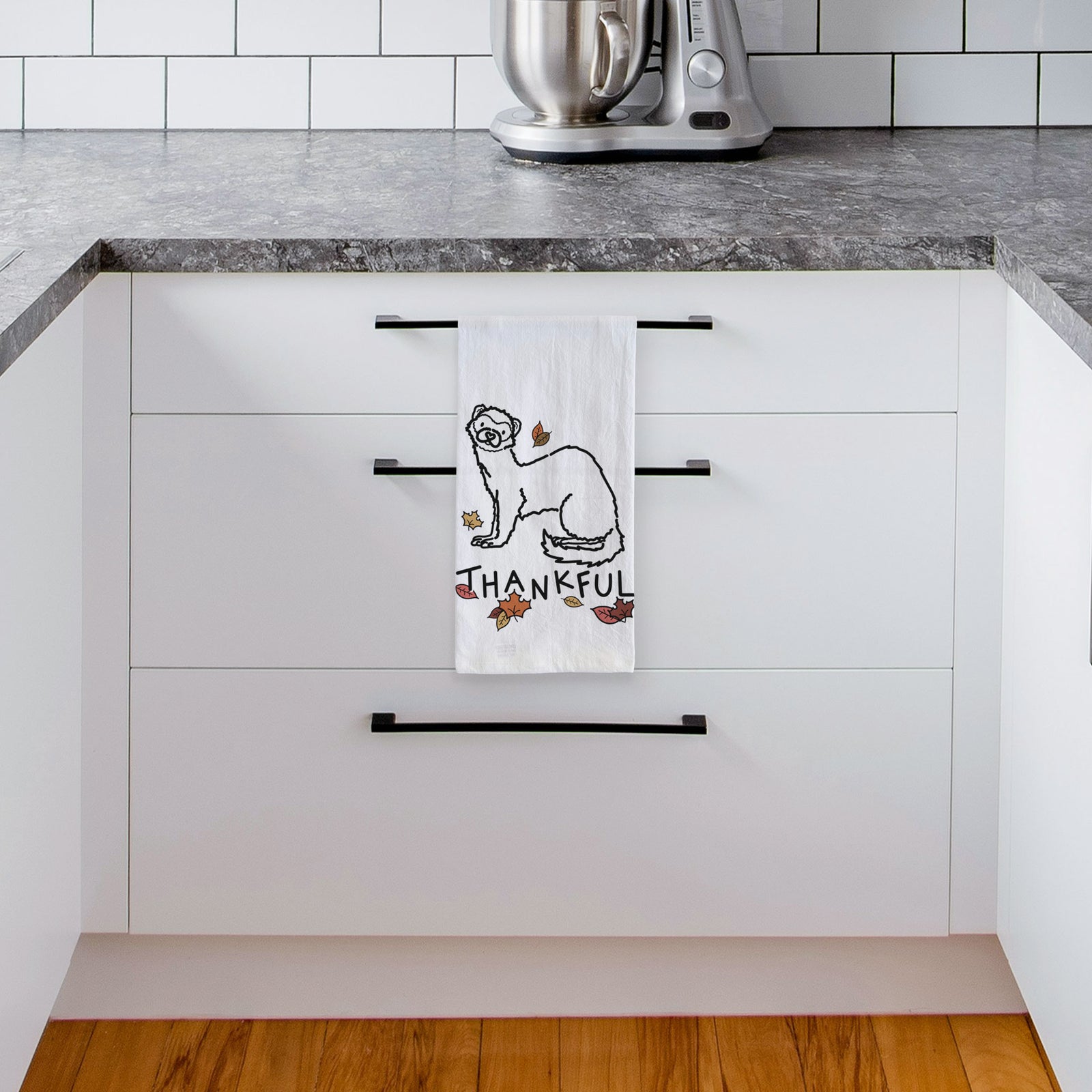 Minimalist line drawing of Fern the Ferret with 'Thankful' lettering on a tea towel, hanging on an oven door in a kitchen
