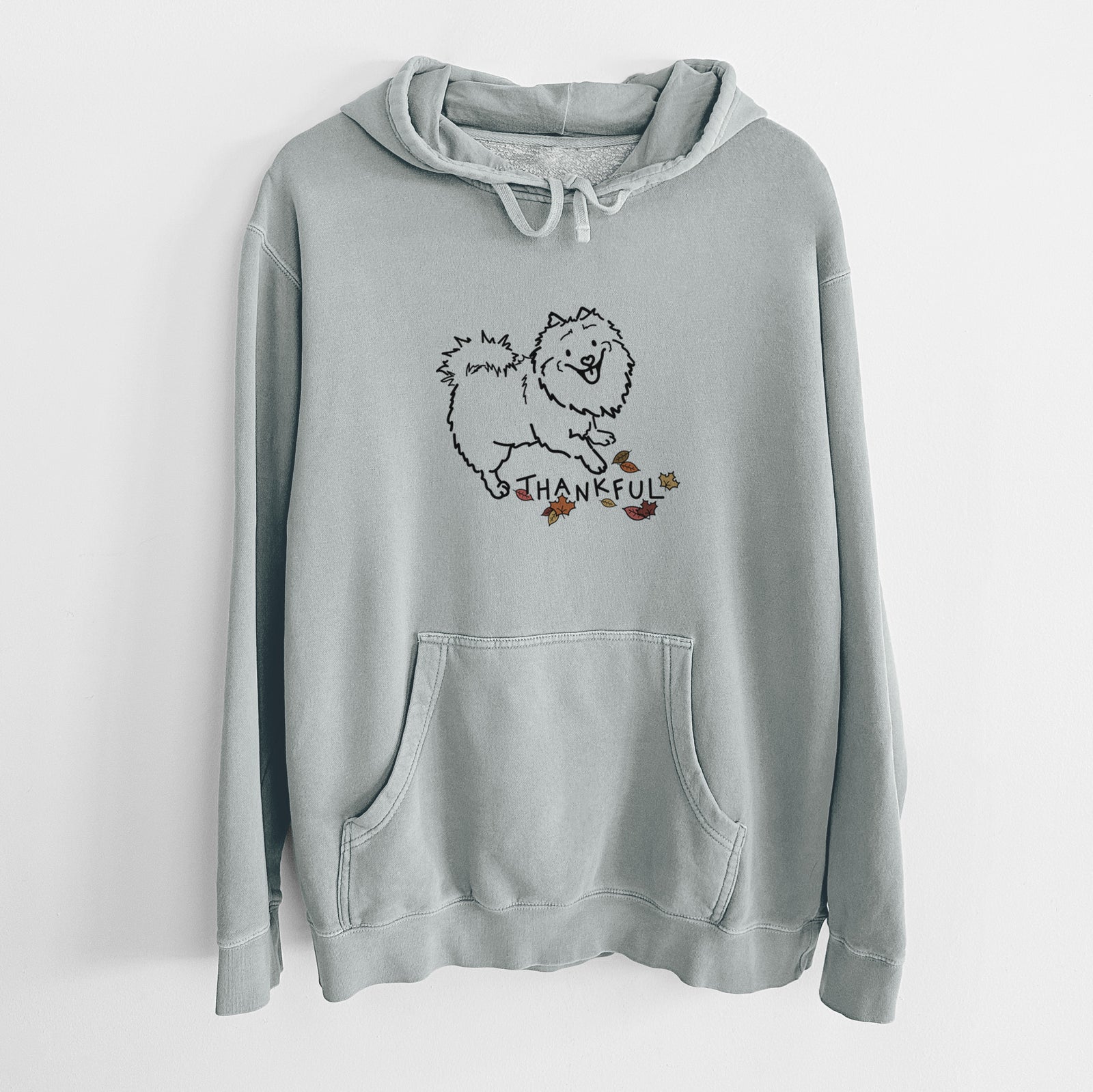 Minimalist line drawing of Goldie the Pomeranian Mix with 'Thankful' lettering on a Sage Unisex pigment dyed hoodie