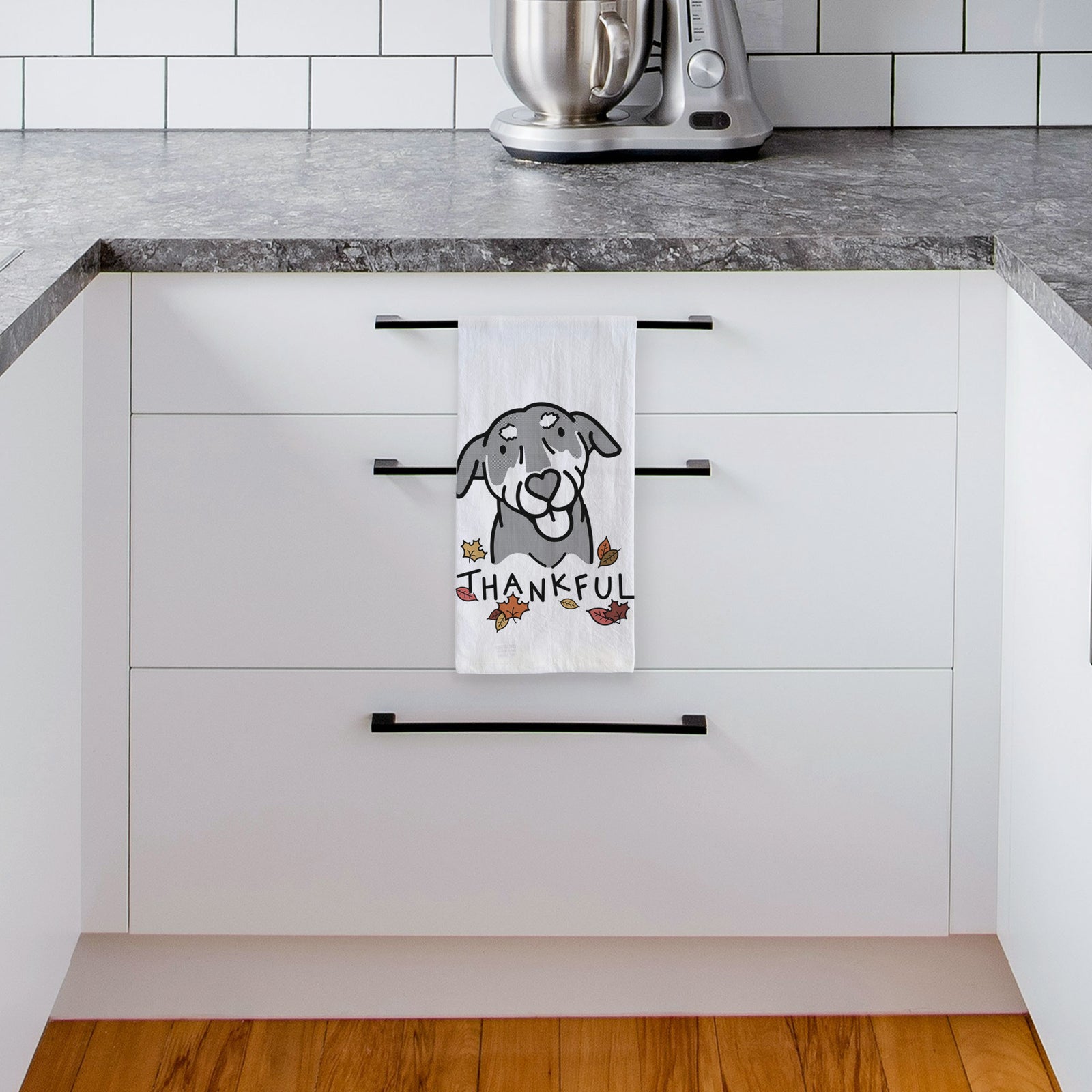 Minimalist line drawing of Lousia the Mixed Breed with 'Thankful' lettering on a tea towel, hanging on an oven door in a kitchen