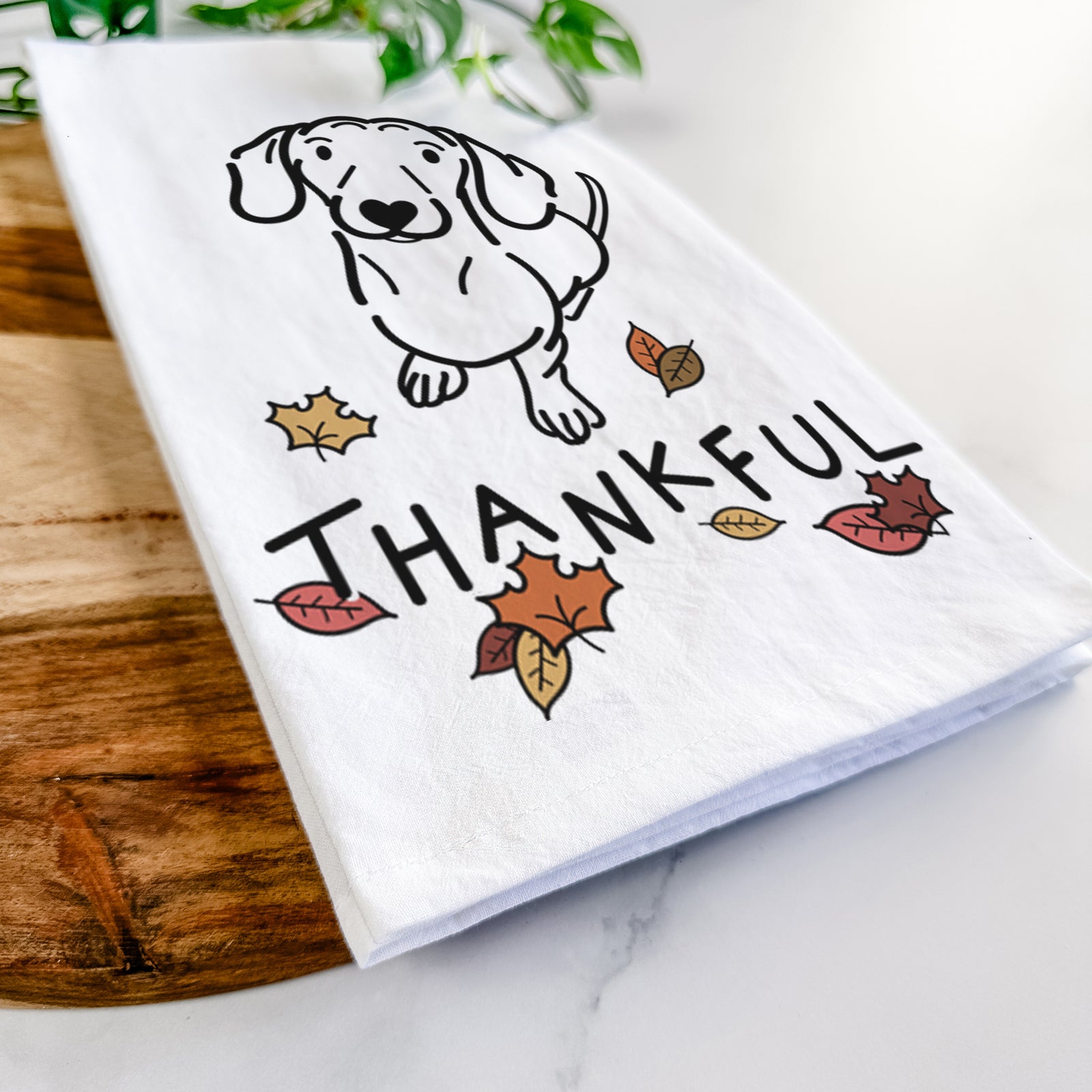 Minimalist line drawing of Moxie the Dachshund with 'Thankful' lettering on a tea towel