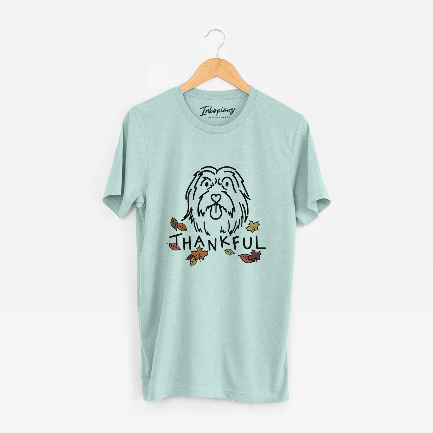 Minimalist line drawing of Tucker the Bearded Collie with 'Thankful' lettering on a Heather Sage Unisex crewneck