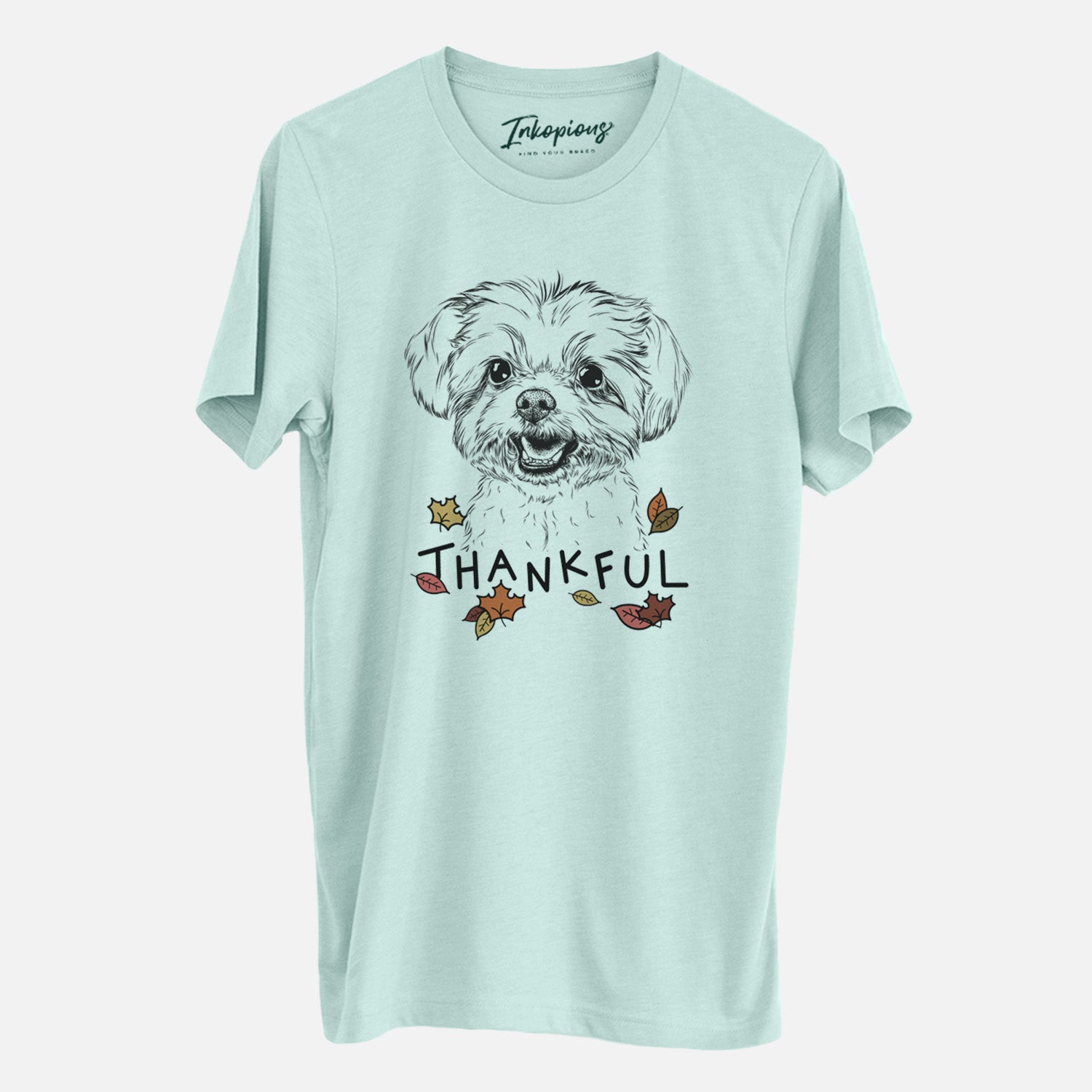Hand-drawn sketch of Aspen the Morkie with 'Thankful' lettering and autumn leaves on a Heather Sage Unisex crewneck