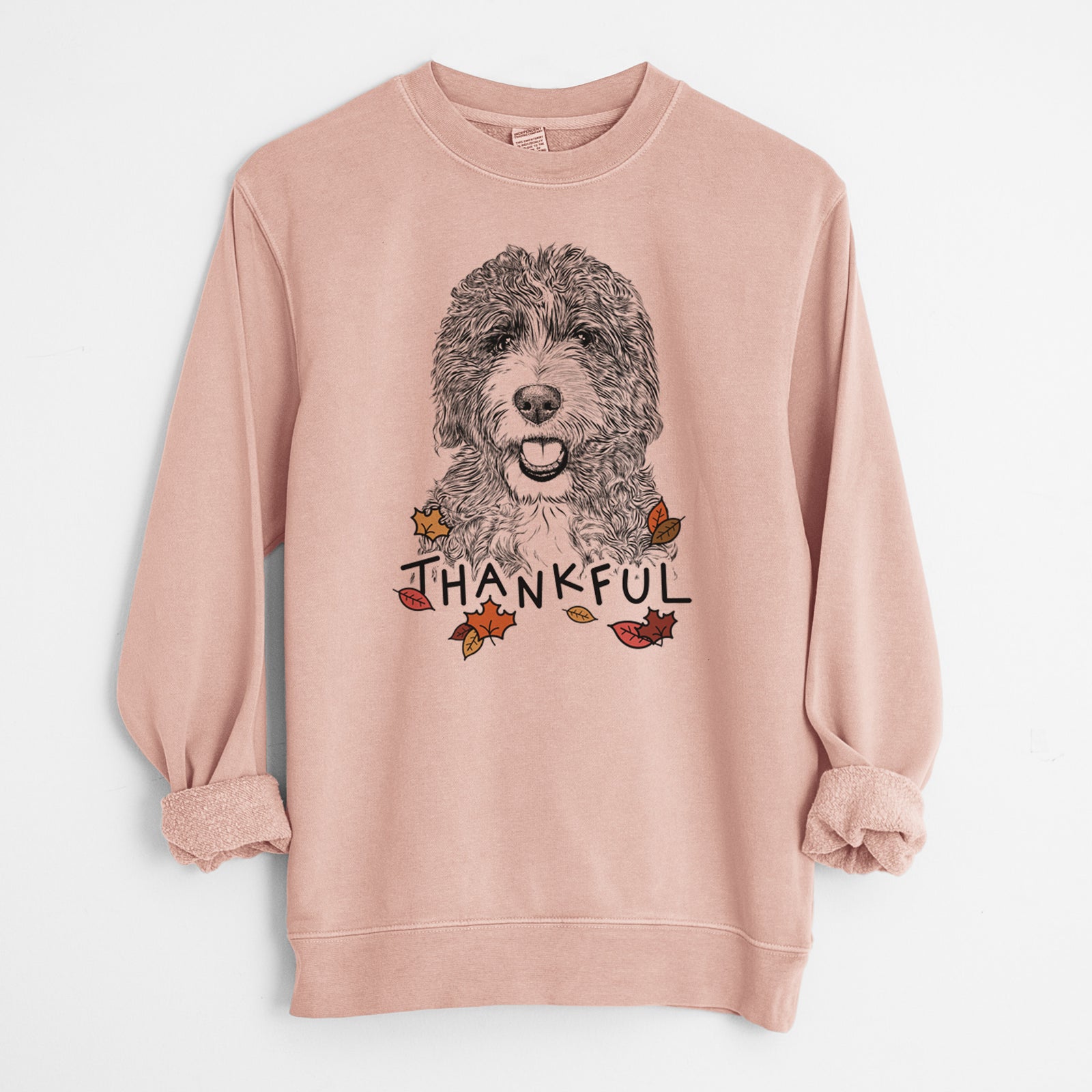 Hand-drawn sketch of Bash the Bernedoodle with 'Thankful' lettering and autumn leaves on a Dusty Pink Unisex pigment dyed crew sweatshirt