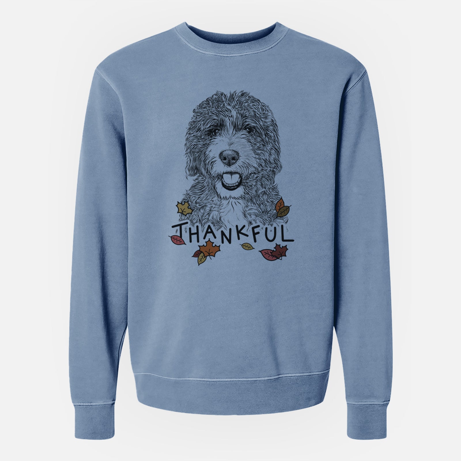 Hand-drawn sketch of Bash the Bernedoodle with 'Thankful' lettering and autumn leaves on a Slate Blue Unisex pigment dyed crew sweatshirt