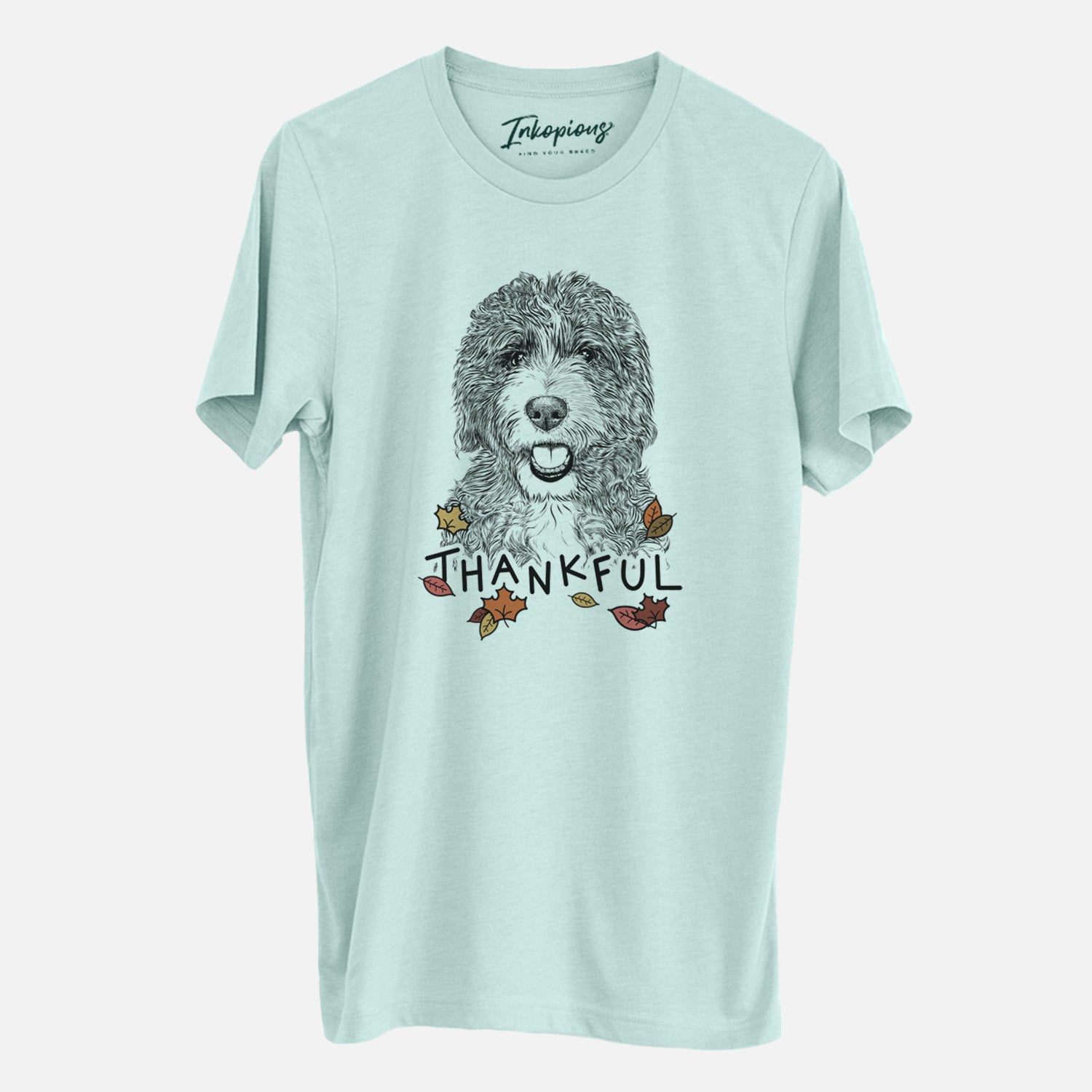 Hand-drawn sketch of Bash the Bernedoodle with 'Thankful' lettering and autumn leaves on a Heather Sage Unisex crewneck