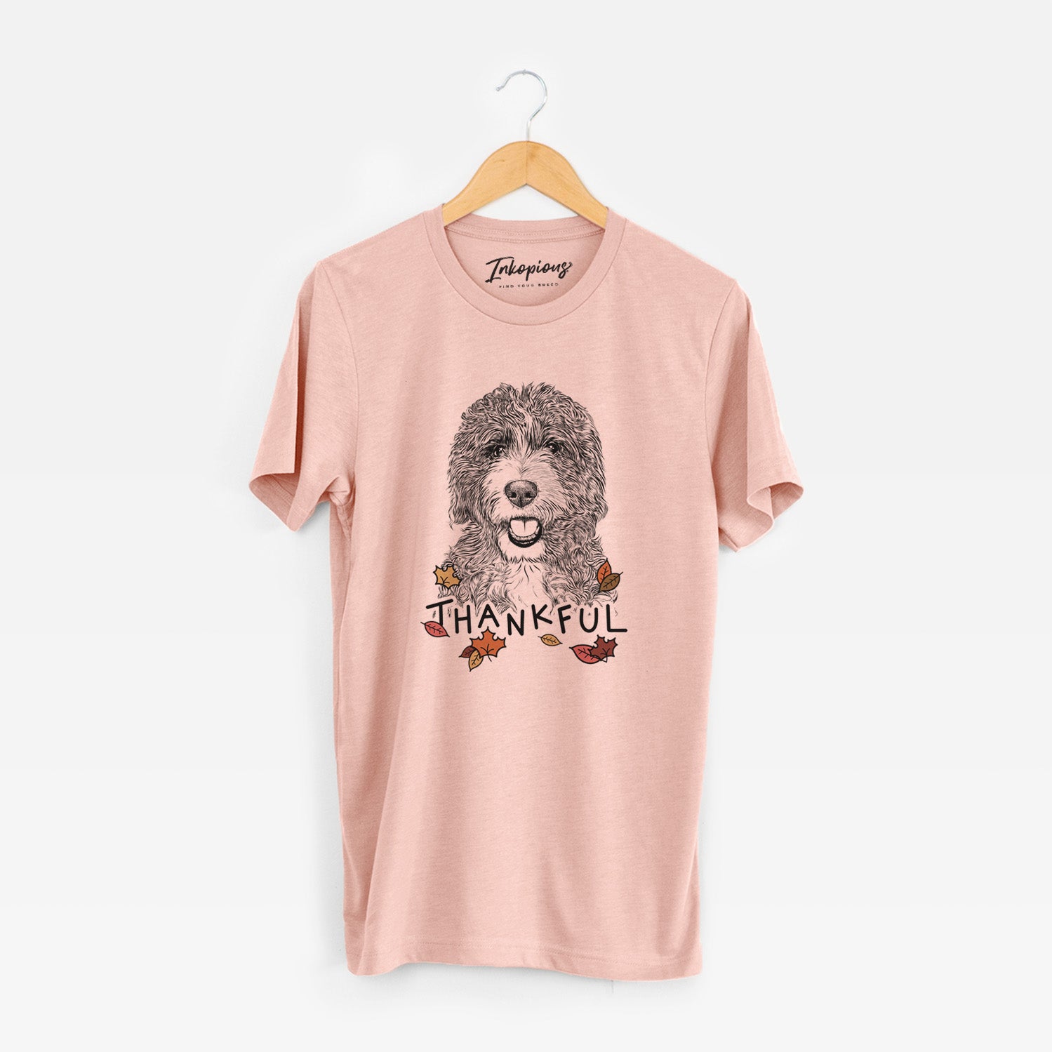 Hand-drawn sketch of Bash the Bernedoodle with 'Thankful' lettering and autumn leaves on a Peach Unisex crewneck