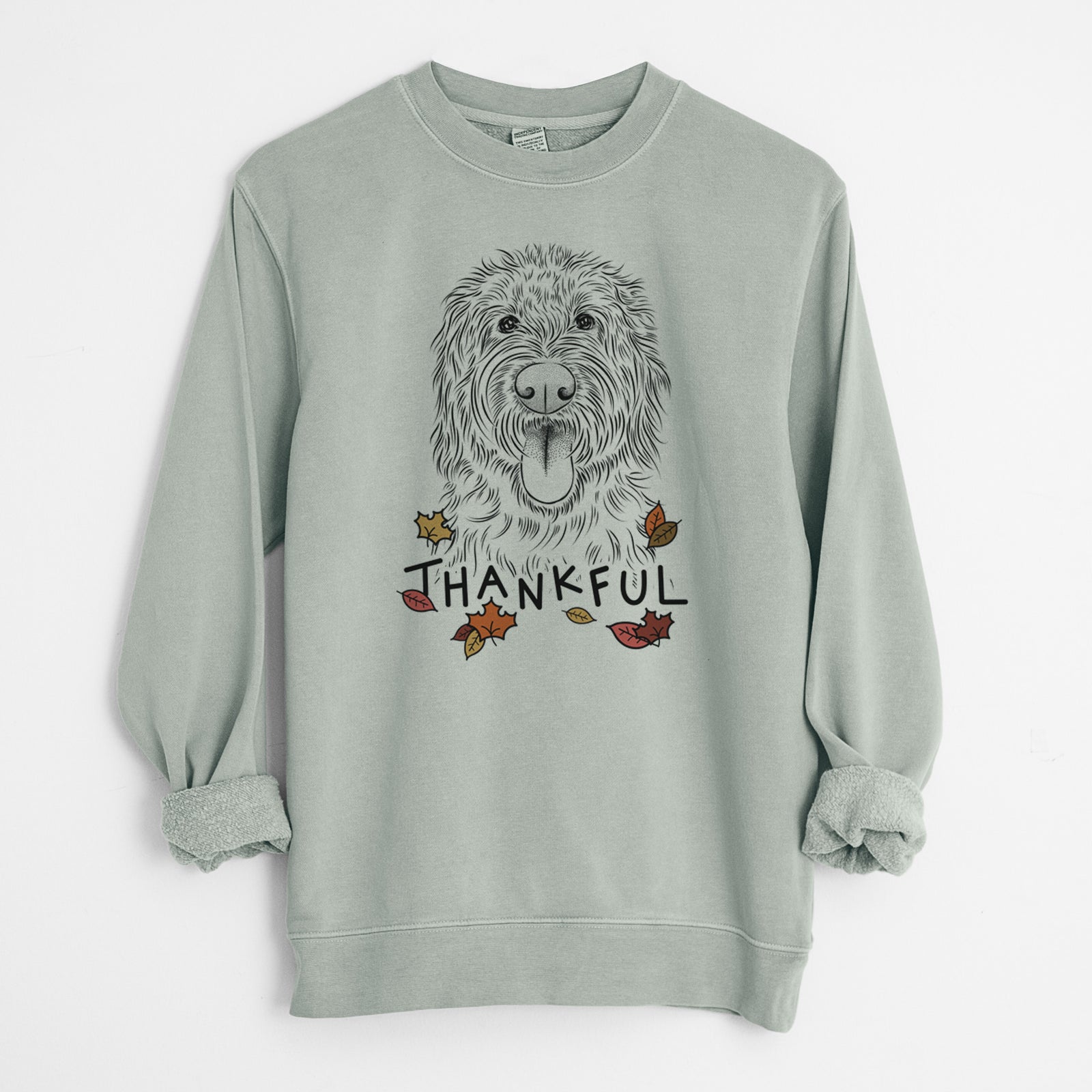 Hand-drawn sketch of Bennett the Doodle with 'Thankful' lettering and autumn leaves on a Sage Unisex pigment dyed crew sweatshirt