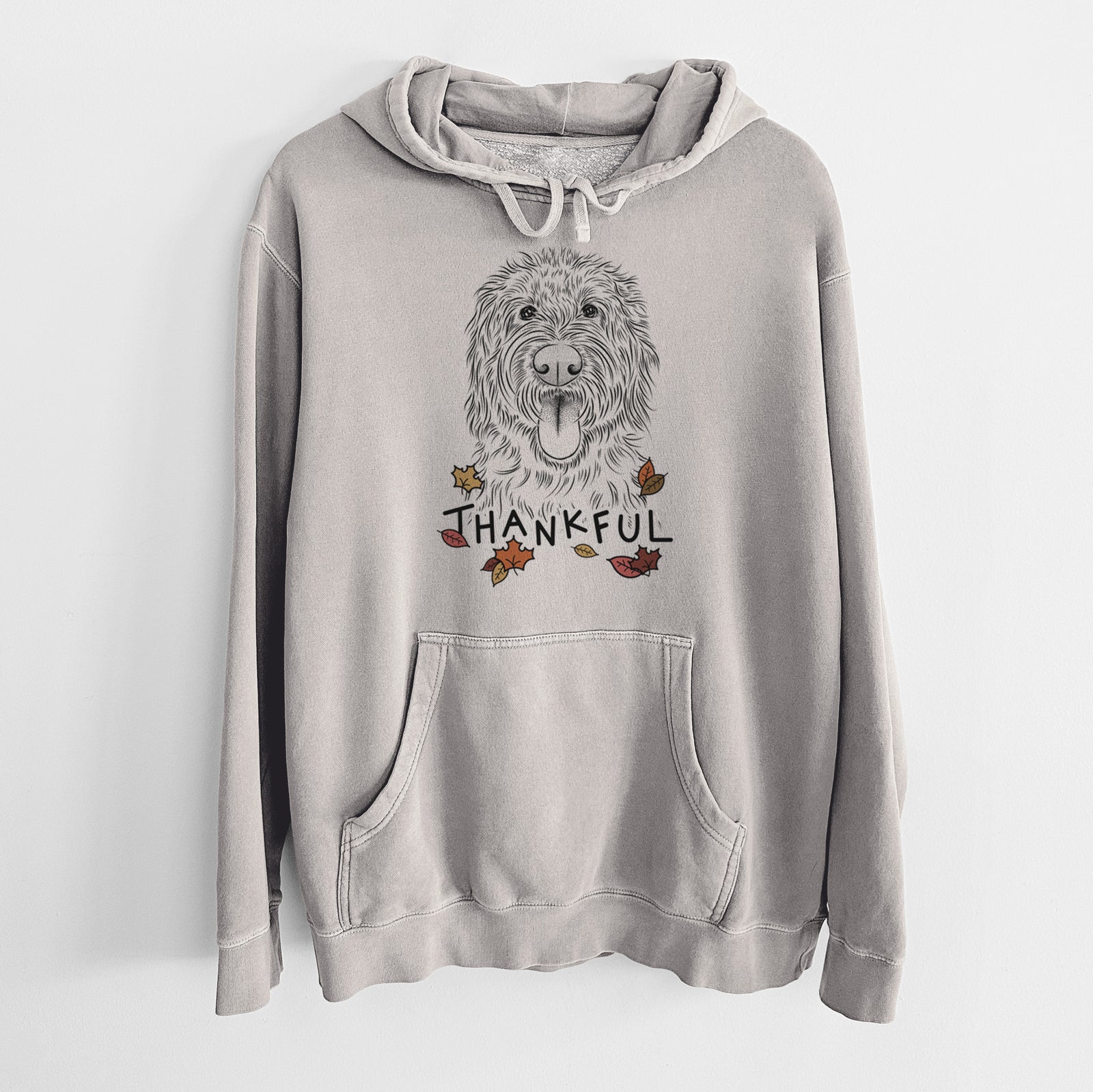 Hand-drawn sketch of Bennett the Doodle with 'Thankful' lettering and autumn leaves on a Cement Unisex pigment dyed hoodie