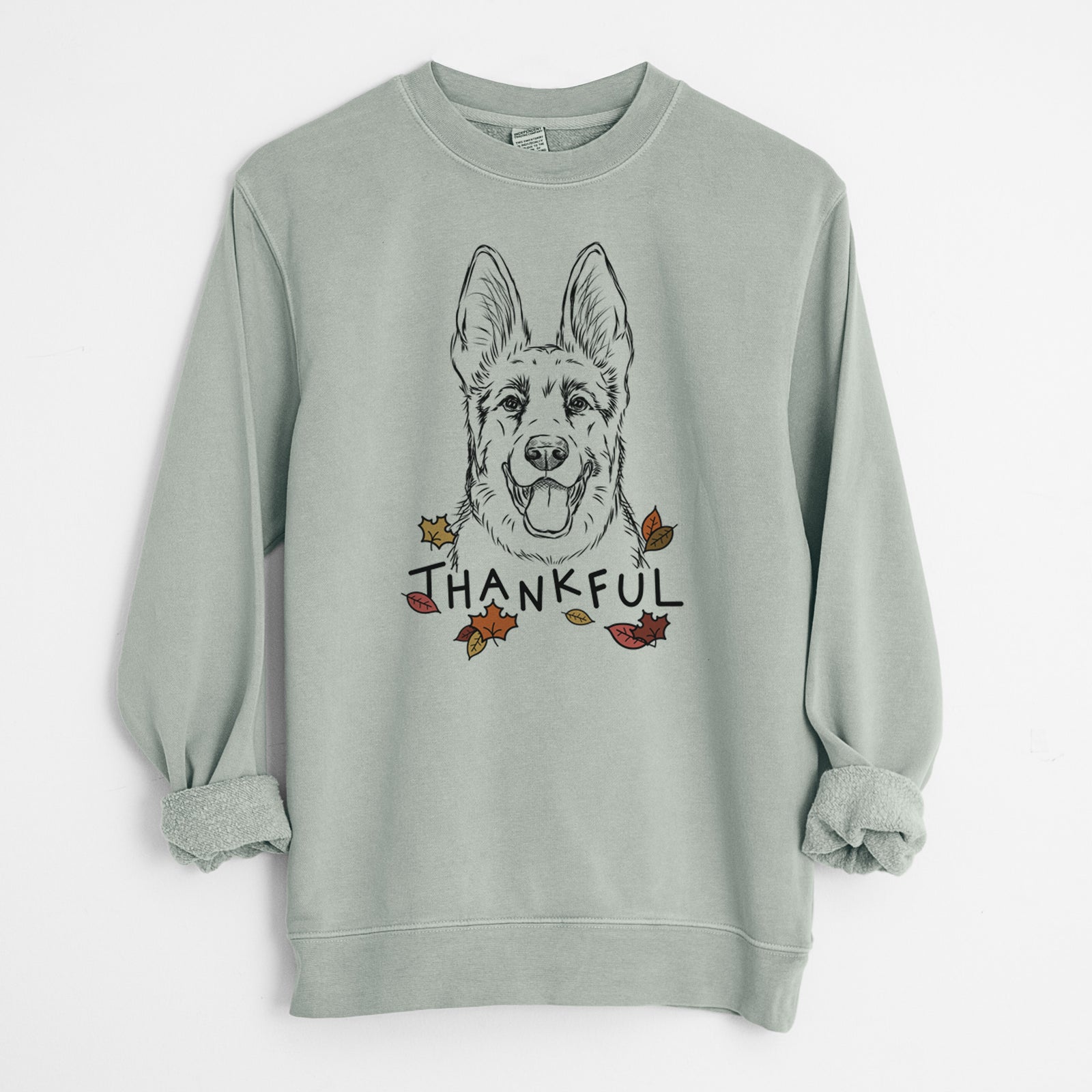 Hand-drawn sketch of Brutus the German Shepherd with 'Thankful' lettering and autumn leaves on a Sage Unisex pigment dyed crew sweatshirt