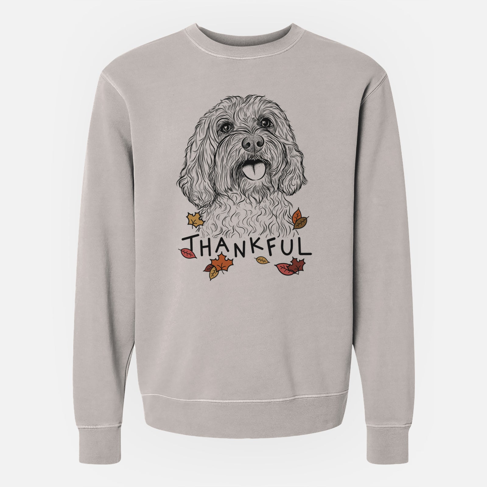 Hand-drawn sketch of Cali the Cavapoo with 'Thankful' lettering and autumn leaves on a Cement Unisex pigment dyed crew sweatshirt