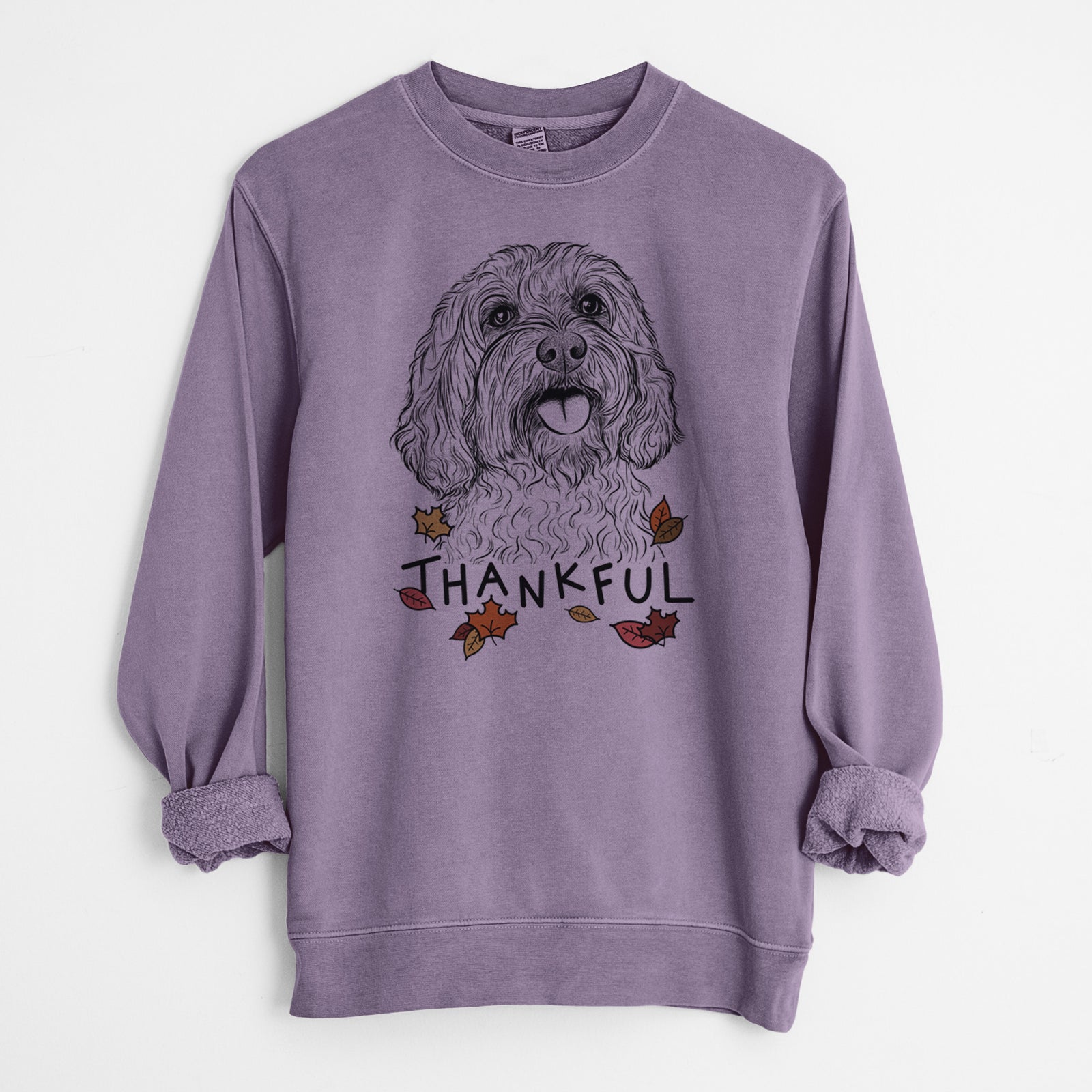 Hand-drawn sketch of Cali the Cavapoo with 'Thankful' lettering and autumn leaves on a Plum Unisex pigment dyed crew sweatshirt