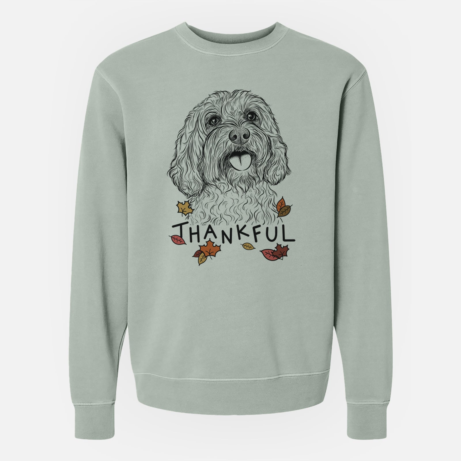Hand-drawn sketch of Cali the Cavapoo with 'Thankful' lettering and autumn leaves on a Sage Unisex pigment dyed crew sweatshirt