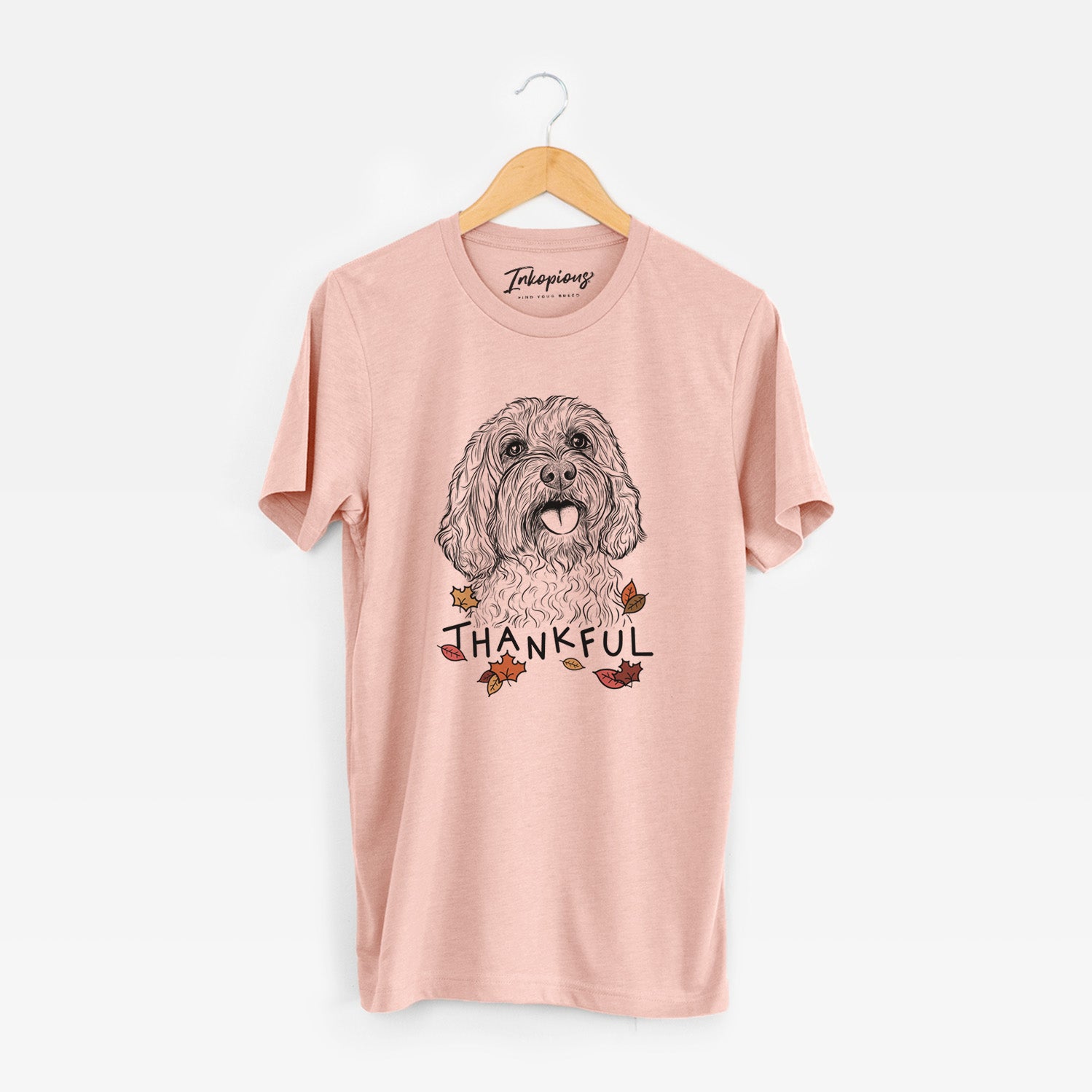 Hand-drawn sketch of Cali the Cavapoo with 'Thankful' lettering and autumn leaves on a Peach Unisex crewneck