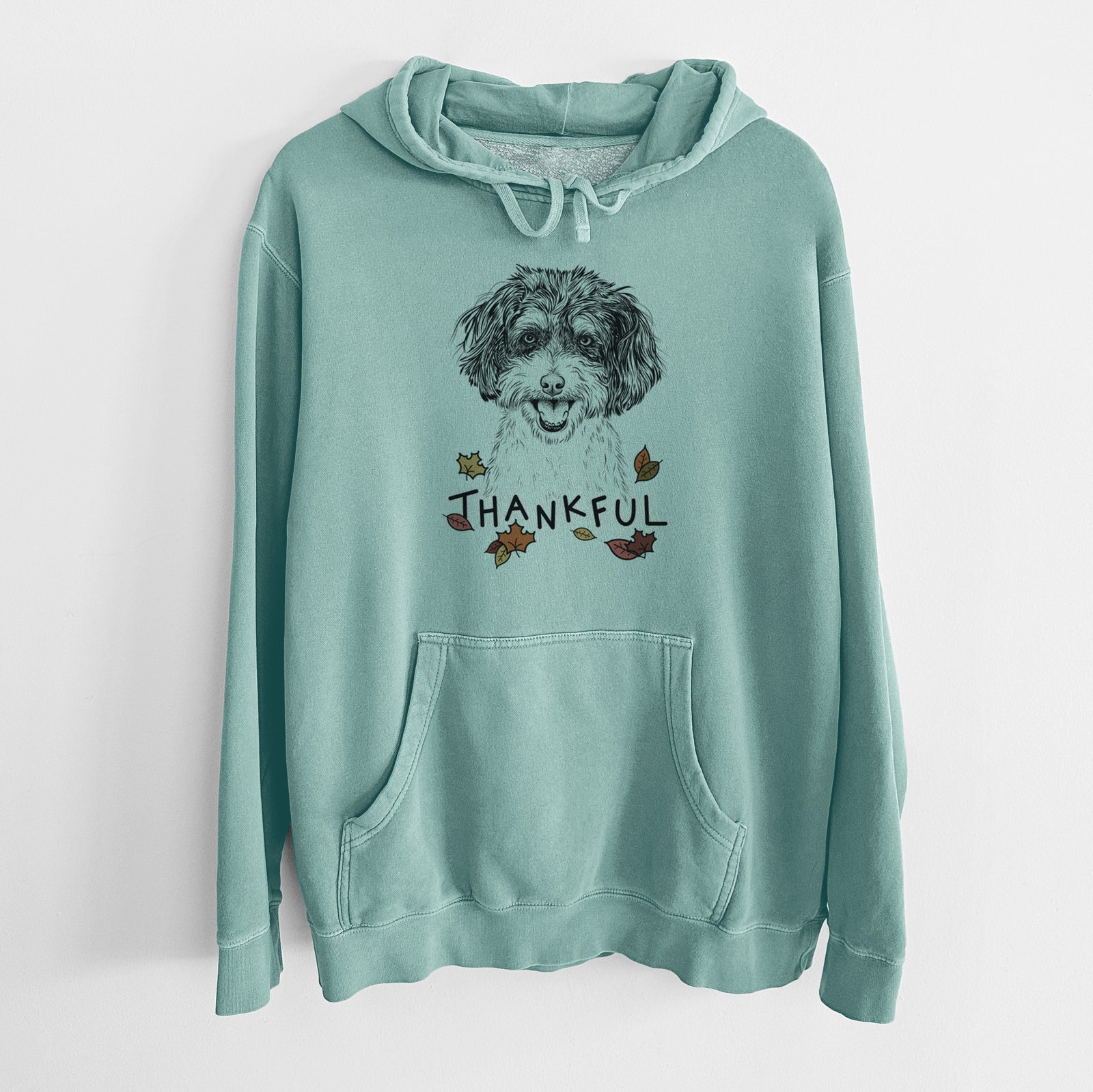 Hand-drawn sketch of Carlos the Cavapoo with 'Thankful' lettering and autumn leaves on a Mint Unisex pigment dyed hoodie