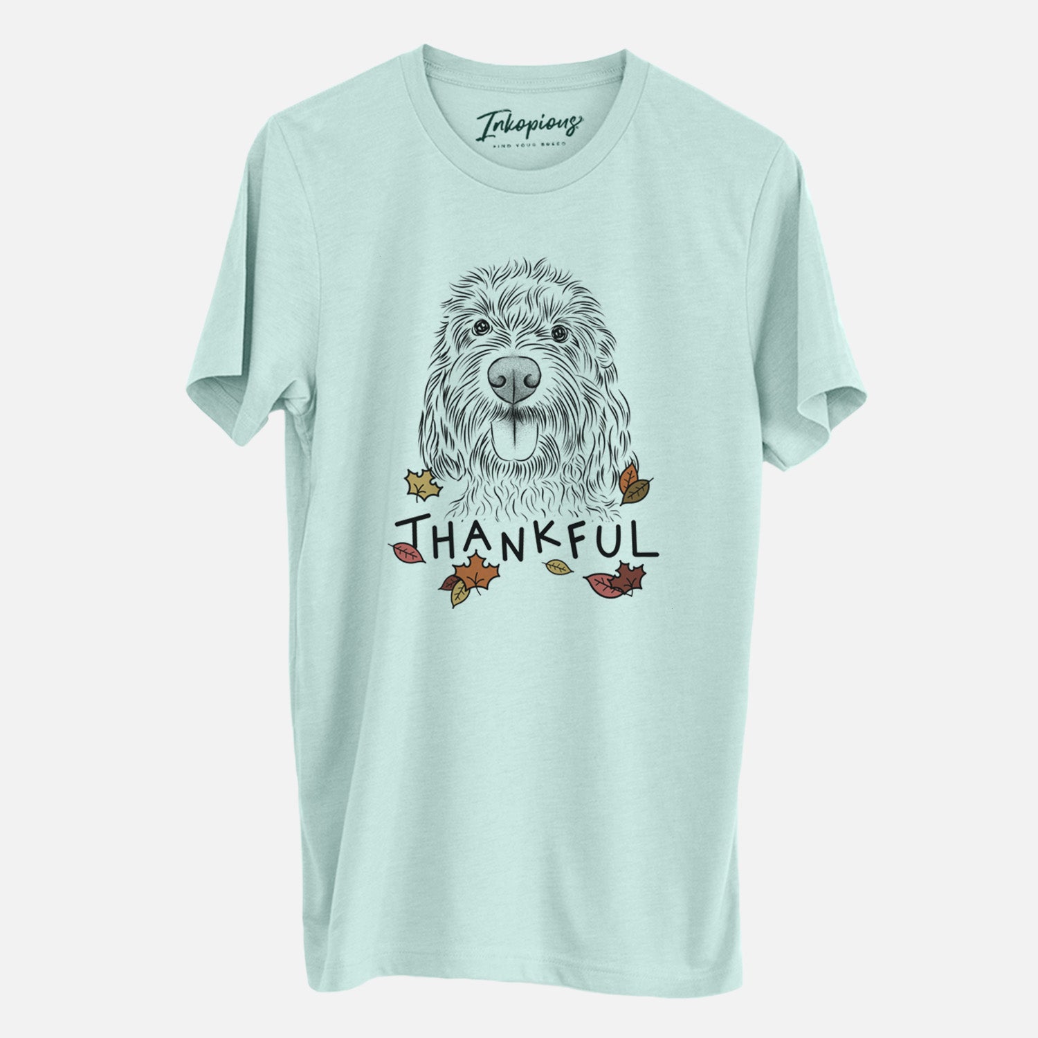 Hand-drawn sketch of Clover the Cockapoo with 'Thankful' lettering and autumn leaves on a Heather Sage Unisex crewneck