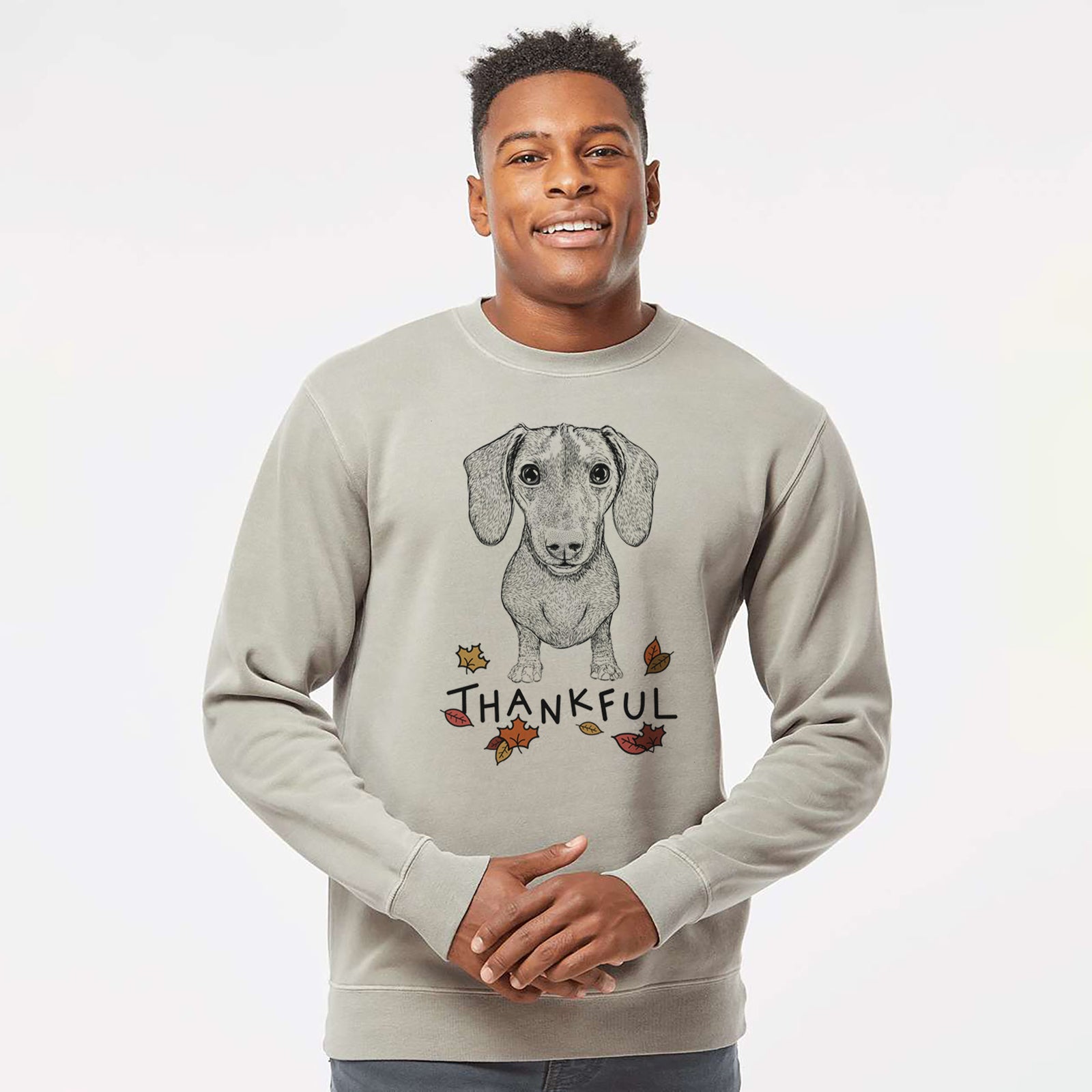 Hand-drawn sketch of Ernie the Mini Dachshund with 'Thankful' lettering and autumn leaves on a Cement Unisex pigment dyed crew sweatshirt