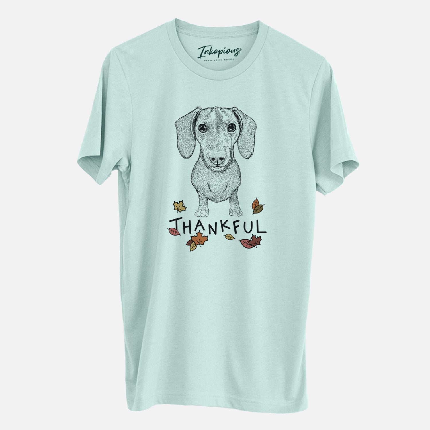 Hand-drawn sketch of Ernie the Mini Dachshund with 'Thankful' lettering and autumn leaves on a Heather Sage Unisex crewneck